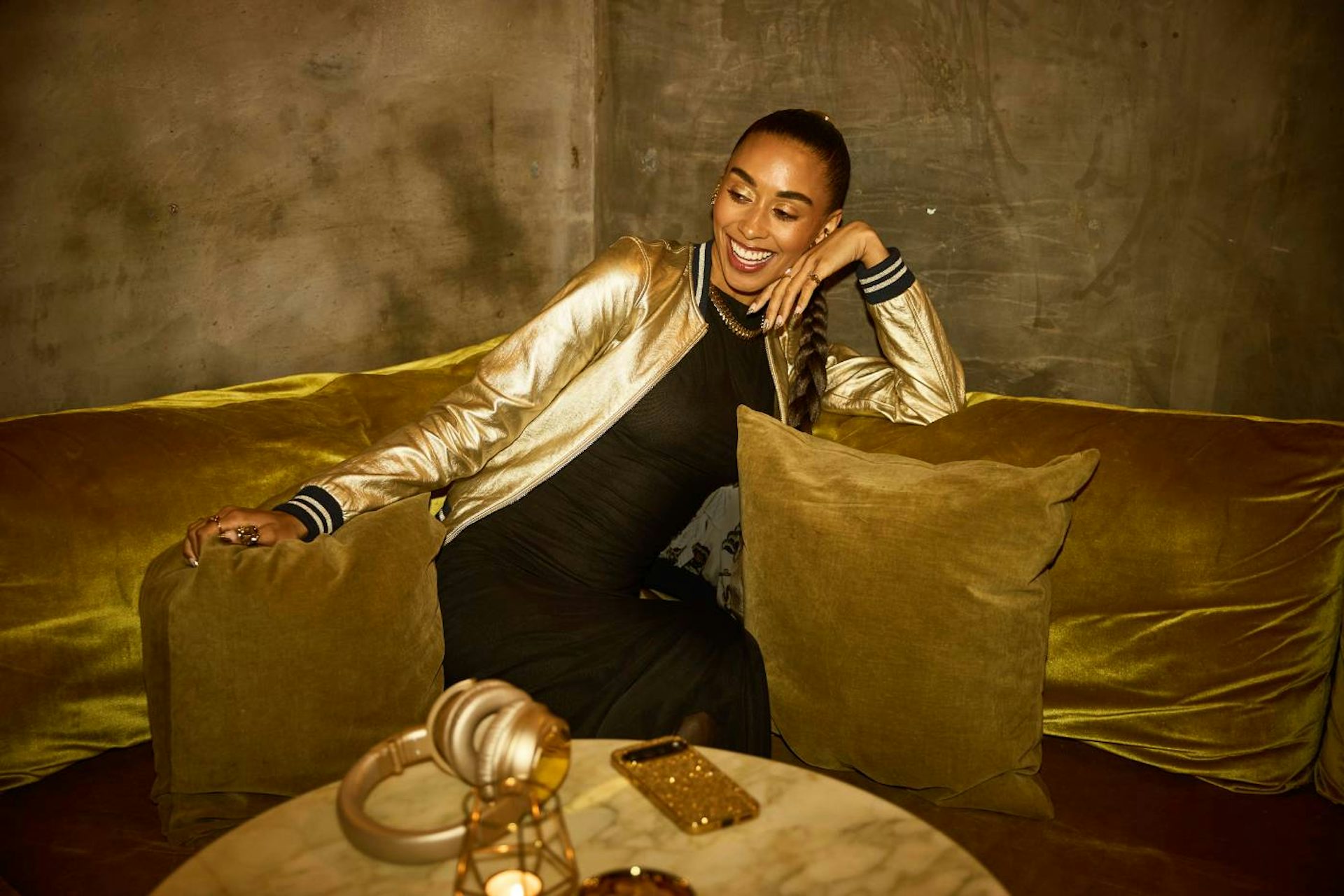 A smiling lady relaxing on a gold coloured couch