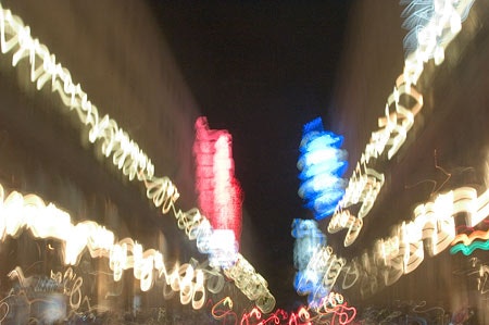 Una foto soffocata di una strada notturna in cui si vede la sfumatura dei luci delle auto e il doppio esposizione che crea un effetto di fusione tra diversi momenti. La fotografia cattura l'energia e l'essenza urbana.