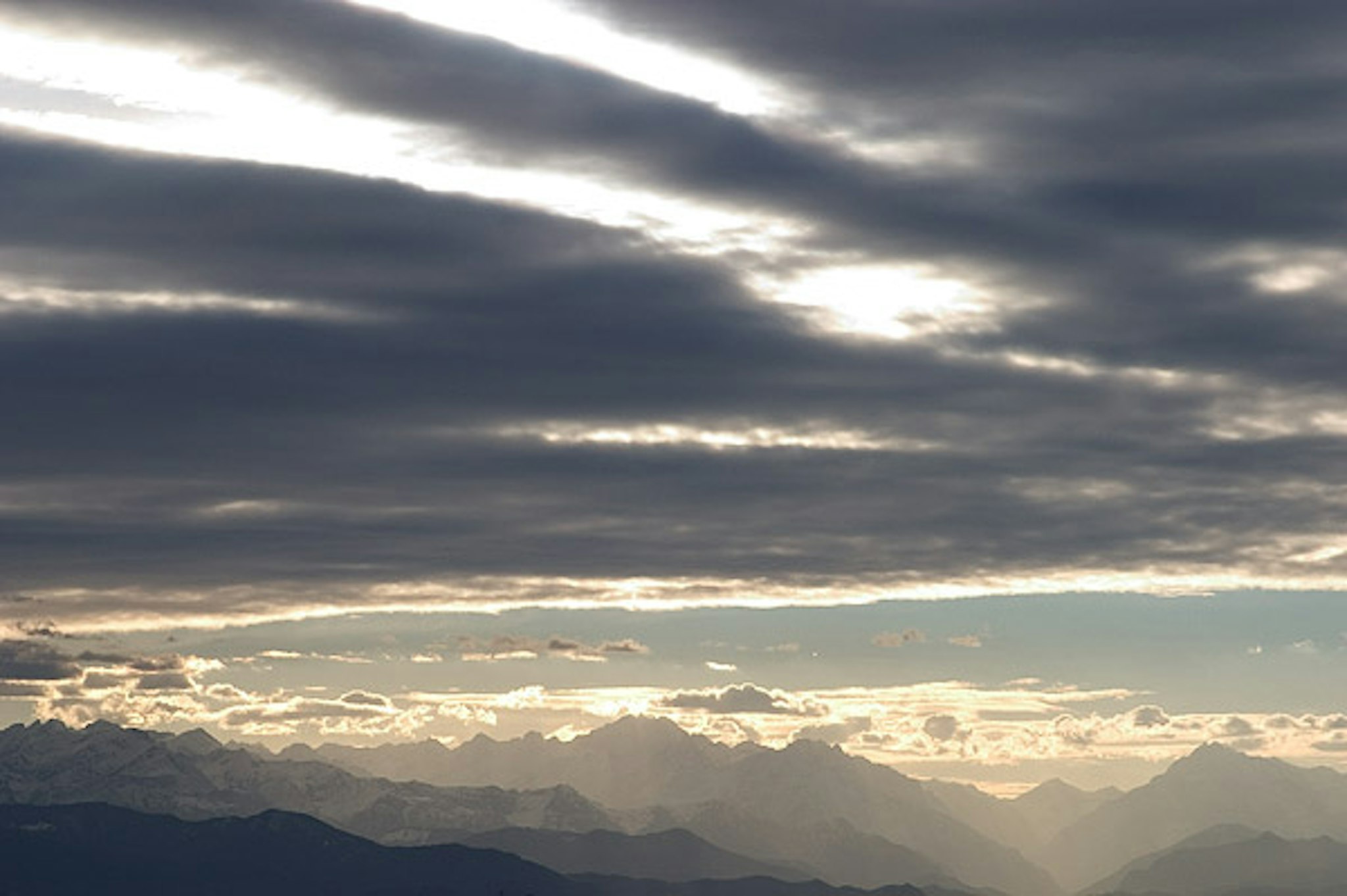 Un'impressionante immagine di un paesaggio montano sotto un cielo nuboso con poche parti cobalto che crea un contrast drammatico.
