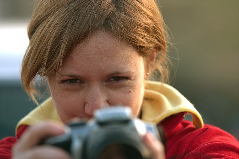 Woman holding camera looking into distance.