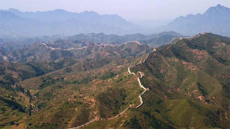Una vasta vista di una strada che curva attorno ad un gruppo di montagne ricoperte da vegetazione verde.