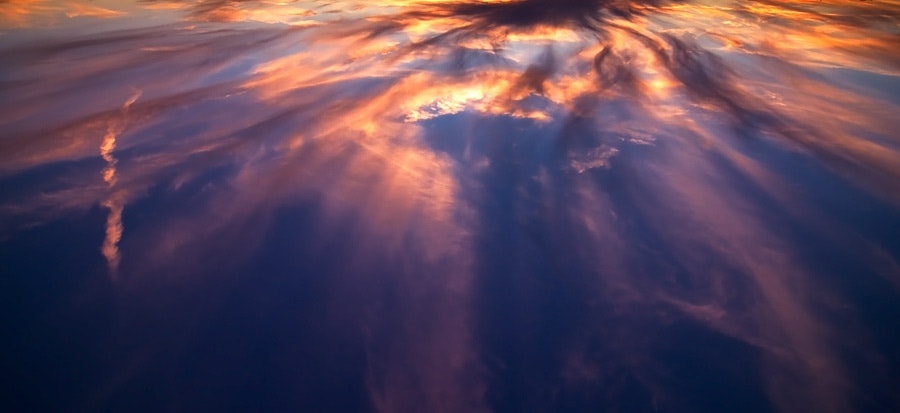 The sky is ablaze with hues of orange and yellow, creating a mesmerizing sunset or sunrise over the horizon.