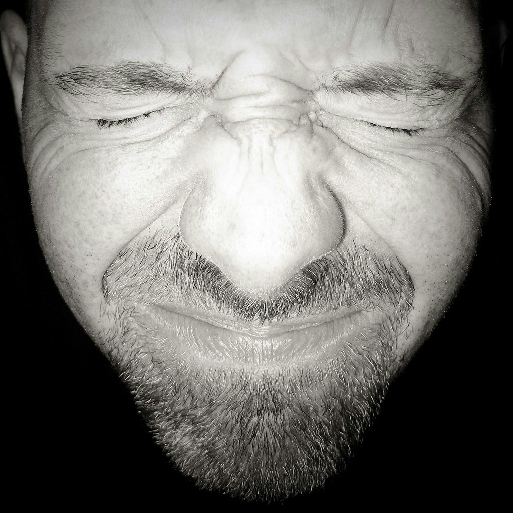 Man with beard showing closed eyes, possibly in pain or deep thought