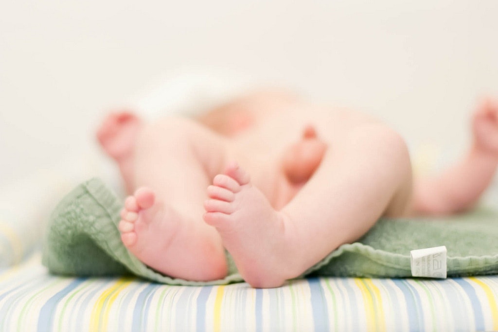 A baby lying down, covered by a blanket.