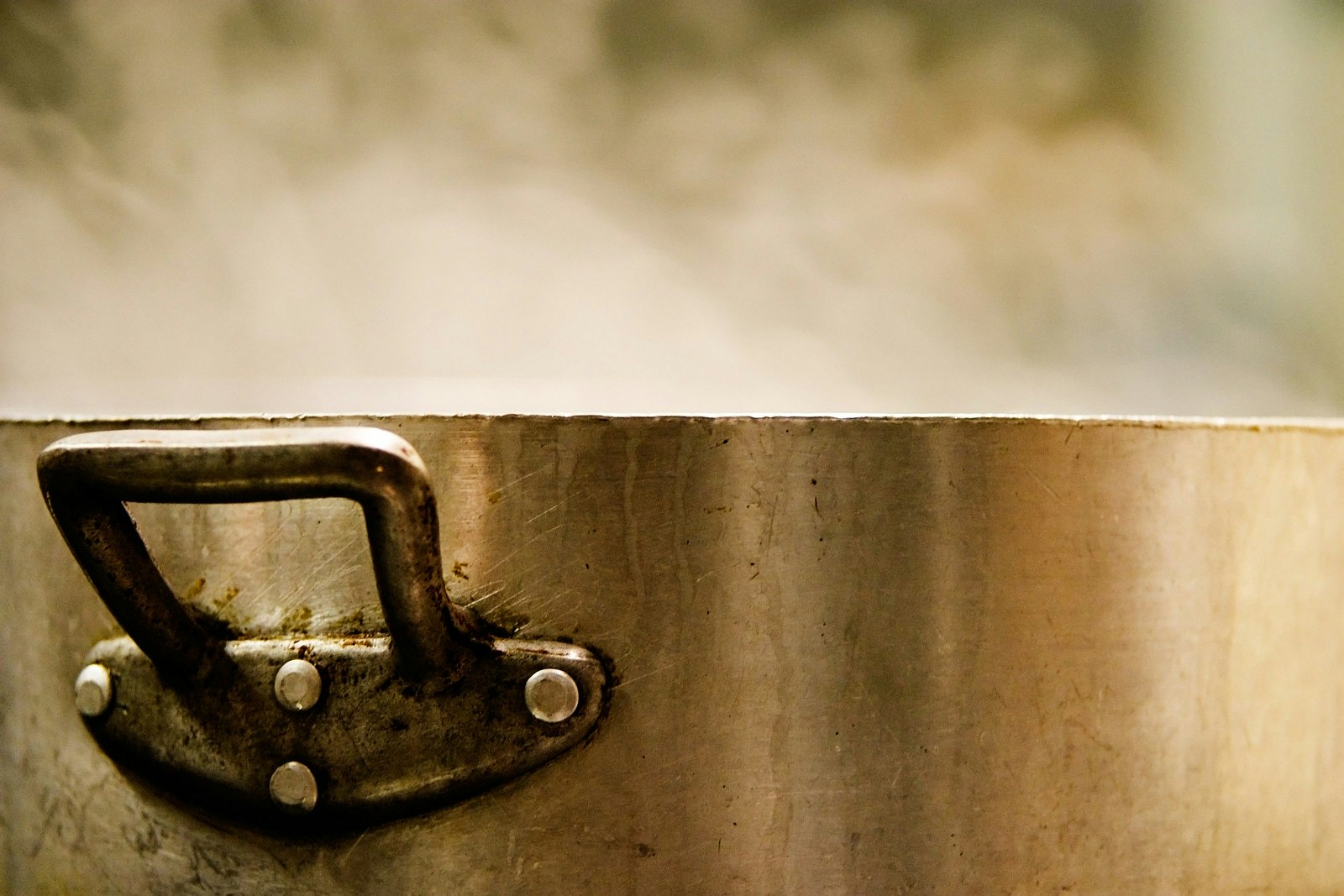 A large stainless steel pot with a lid on a stove, ready to be cooked over.