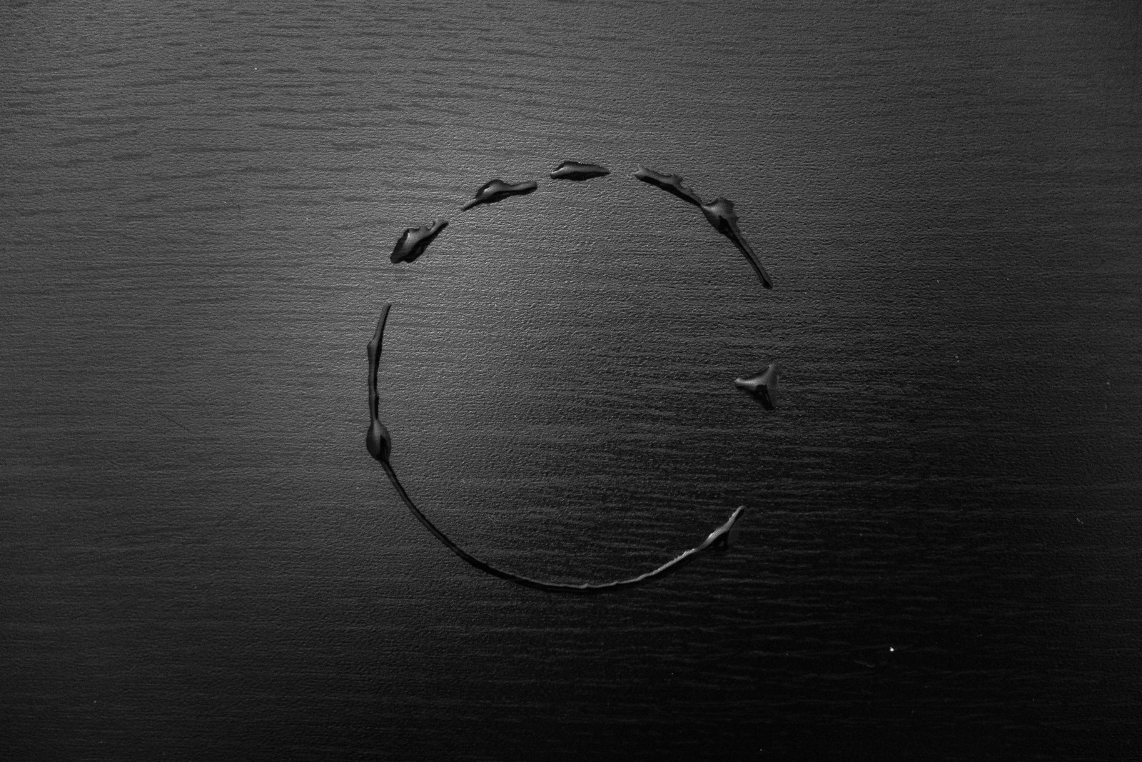 A round circle of wire with six circular holes, set against a dark background.