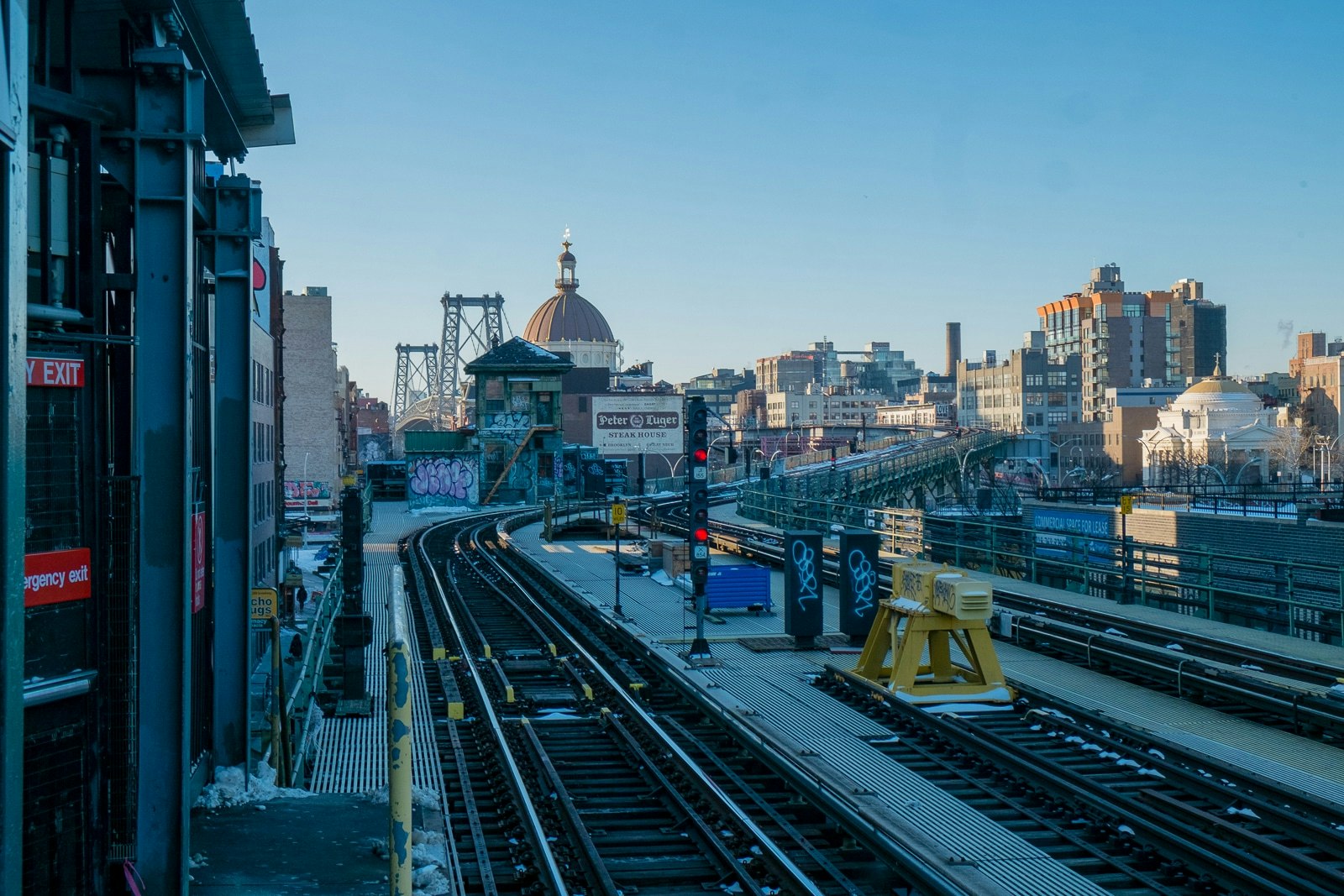 Citta scorrevole, rotaie ferroviarie, grattacielo con torre oraria grande, ponte.