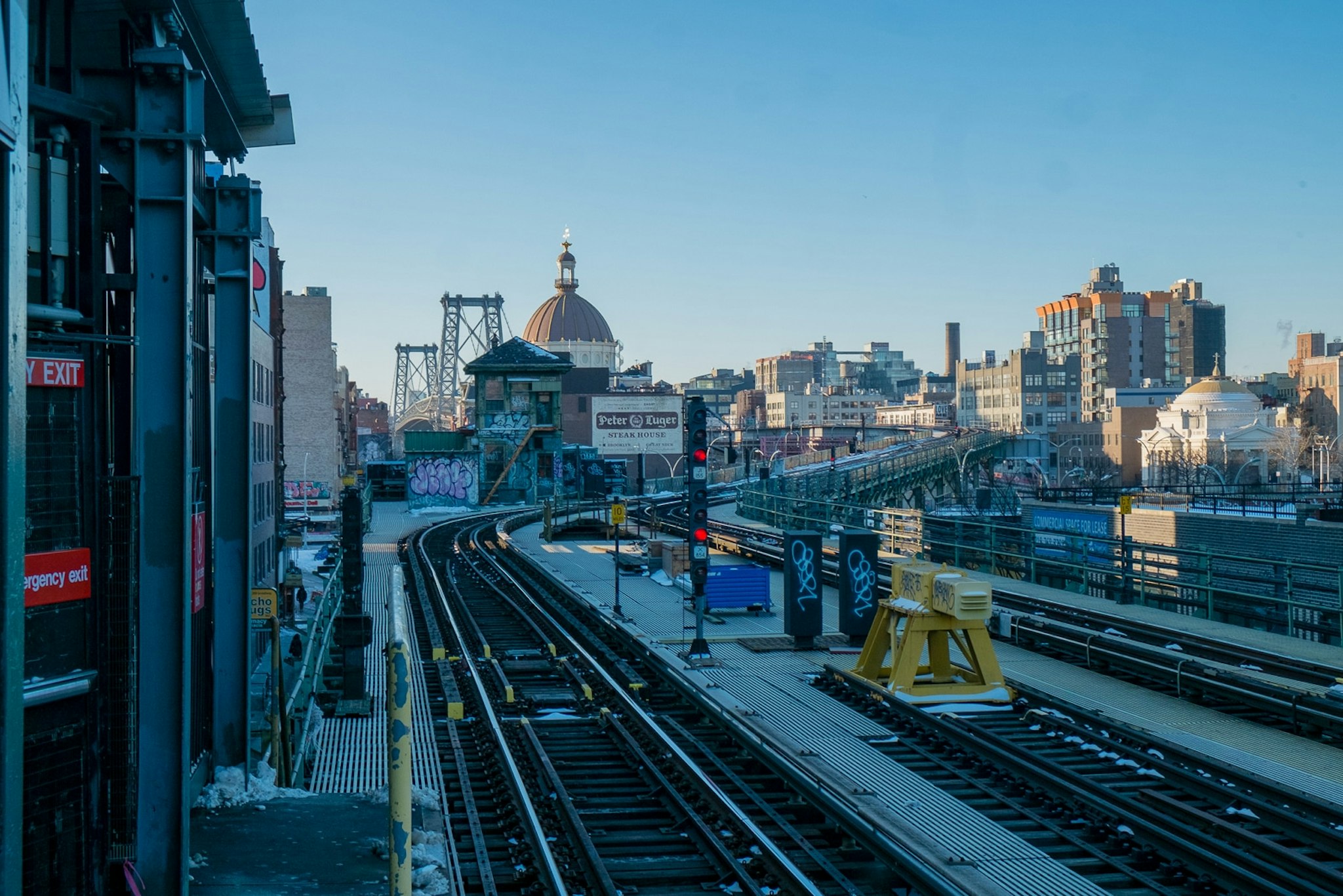 Citta scorrevole, rotaie ferroviarie, grattacielo con torre oraria grande, ponte.