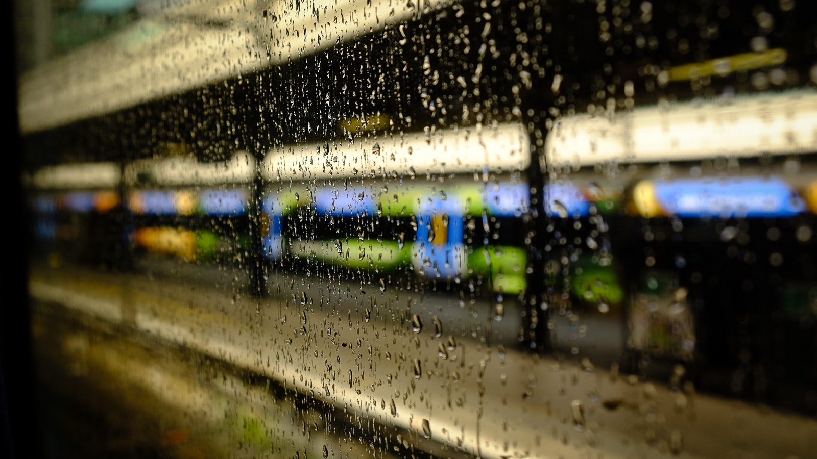 Drops of rain on glass, outside scene with a storefront and rain-streaked window.