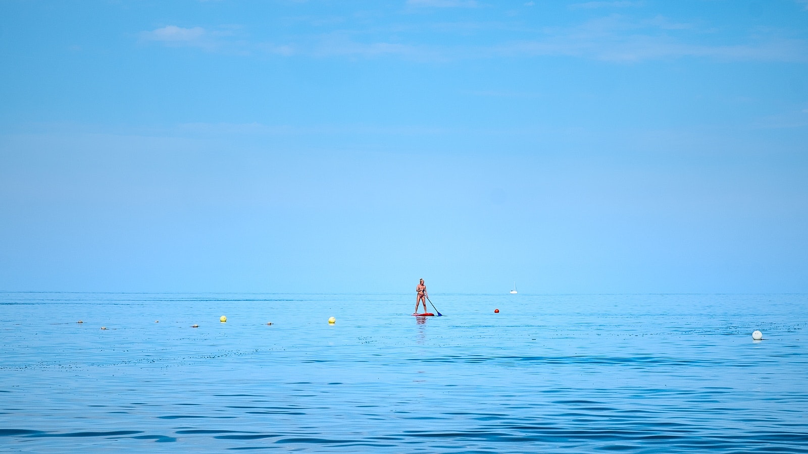 A wide ocean view with boats floating on the surface of blue water.