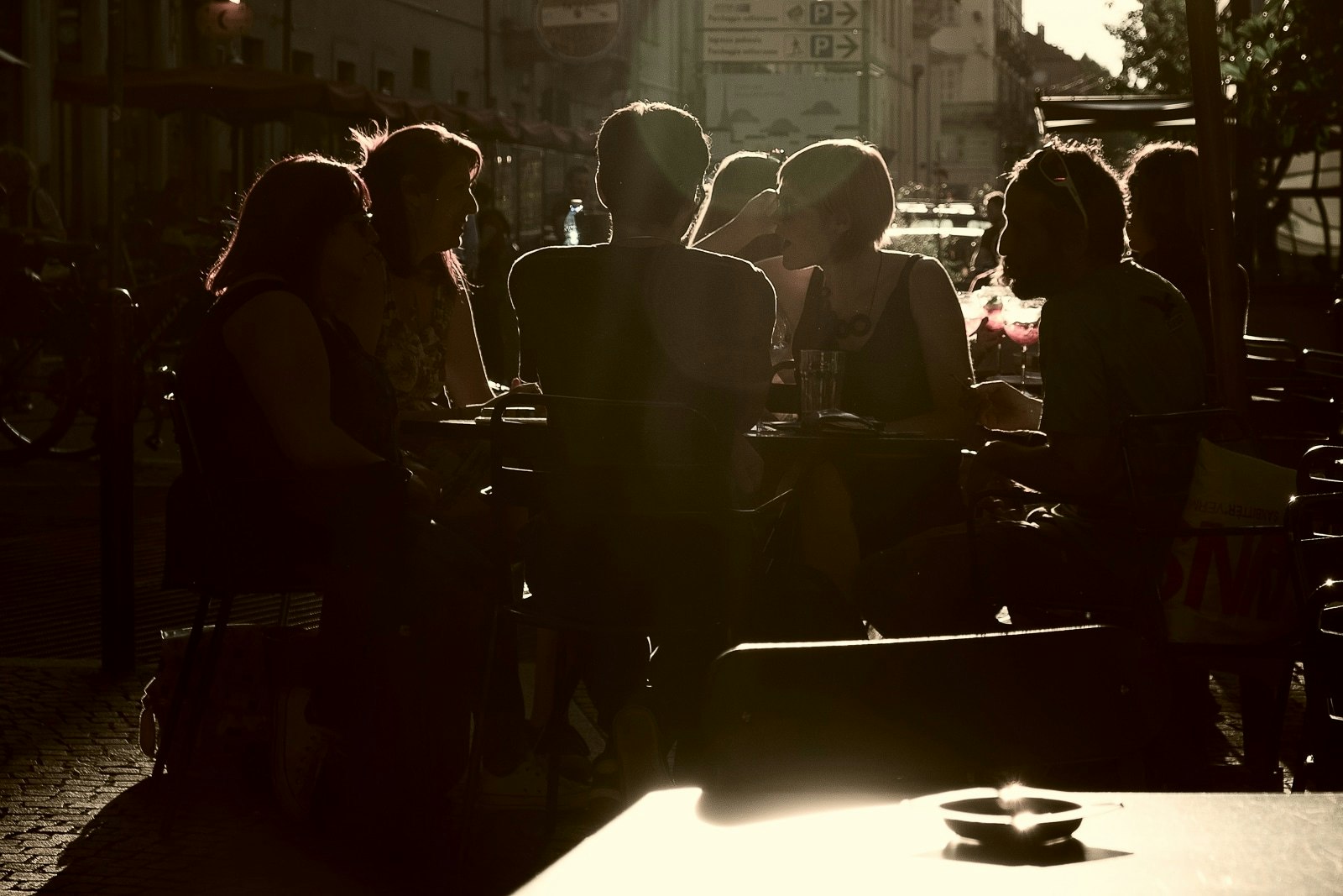People sitting at outdoor cafe tables, enjoying a sunny day