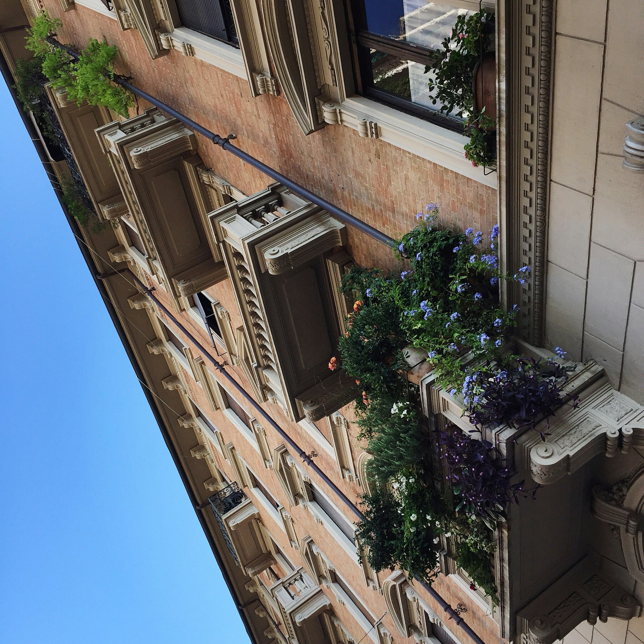 Multi-story residential building with balconies, potted plants, and decorative architectural elements.
