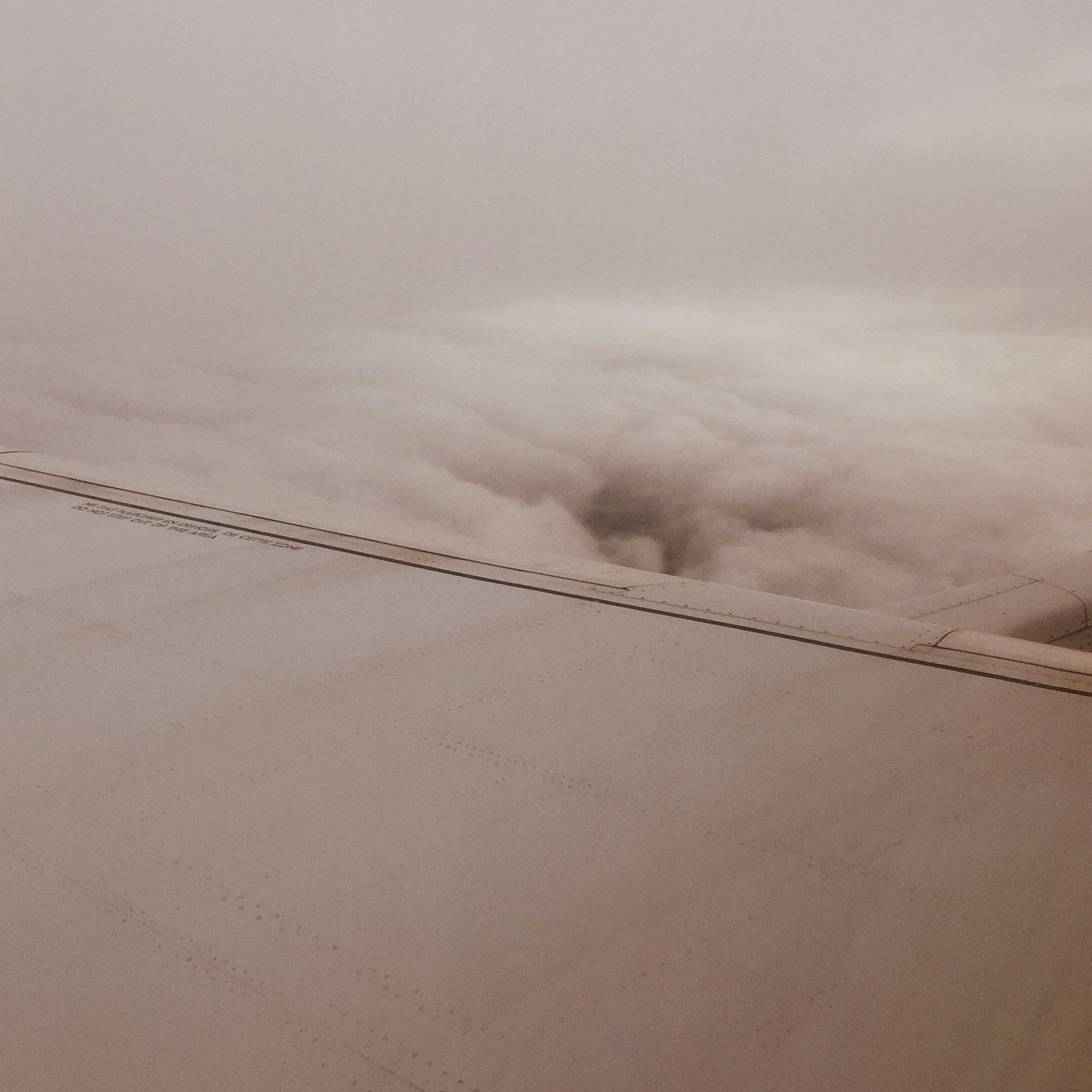 A cloudy sky with a break in the clouds revealing the clear sky below.