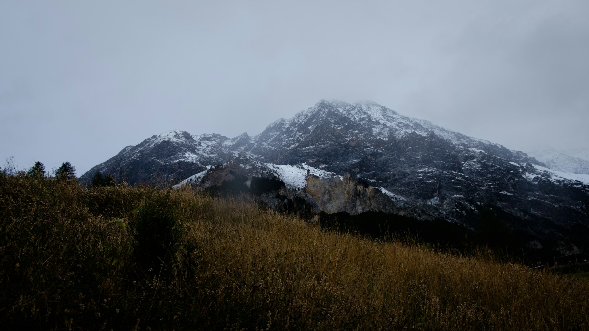 A panoramic view of a snow-covered mountain under a gray sky.