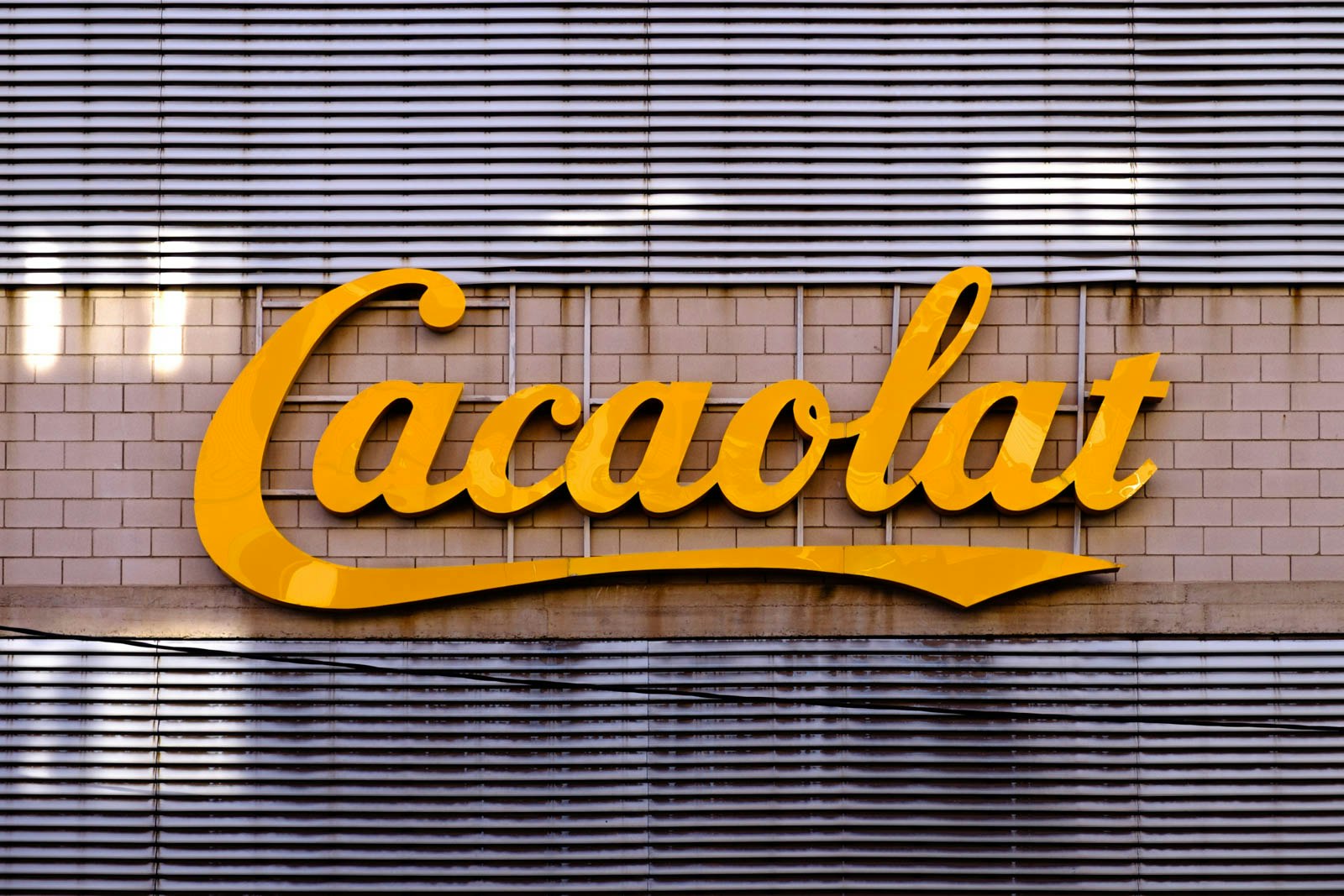 Cacaolat factory sign with lights on behind it.