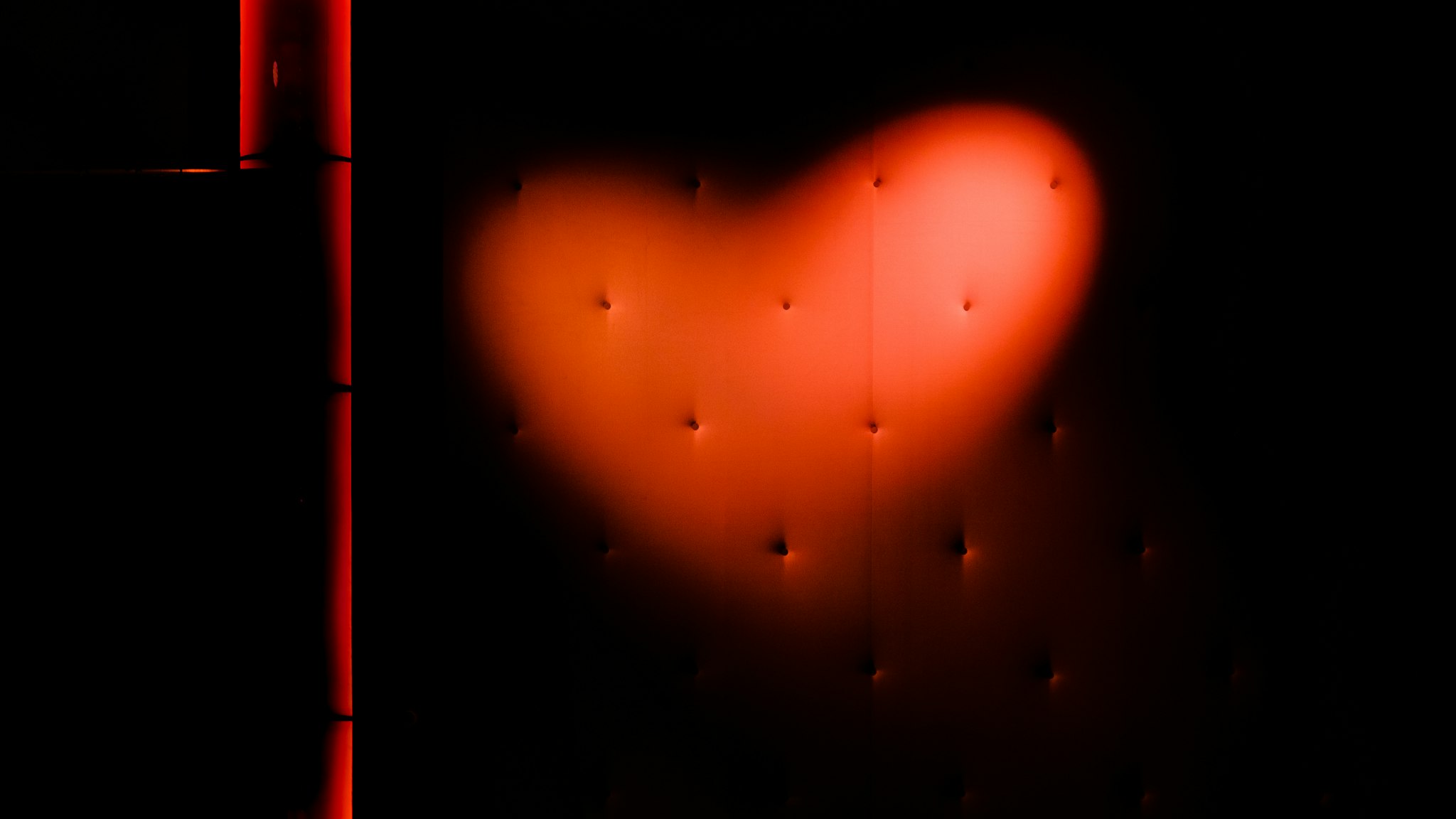 A photo of a heart shape made with the camera flash on a dark background.