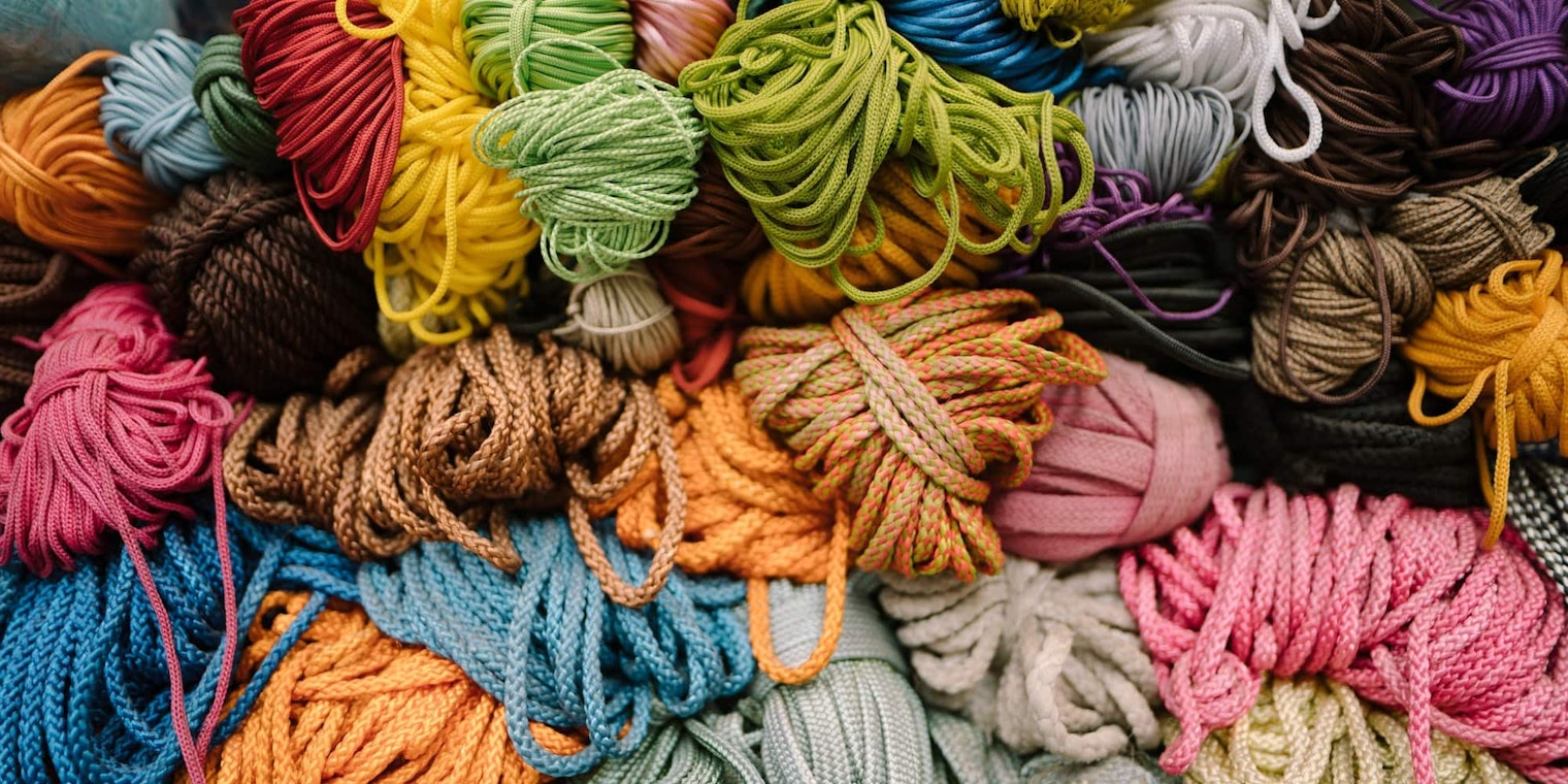A messy pile of unkempt yarn skeins in a variety of colors, sizes, and thickeses of yarn.