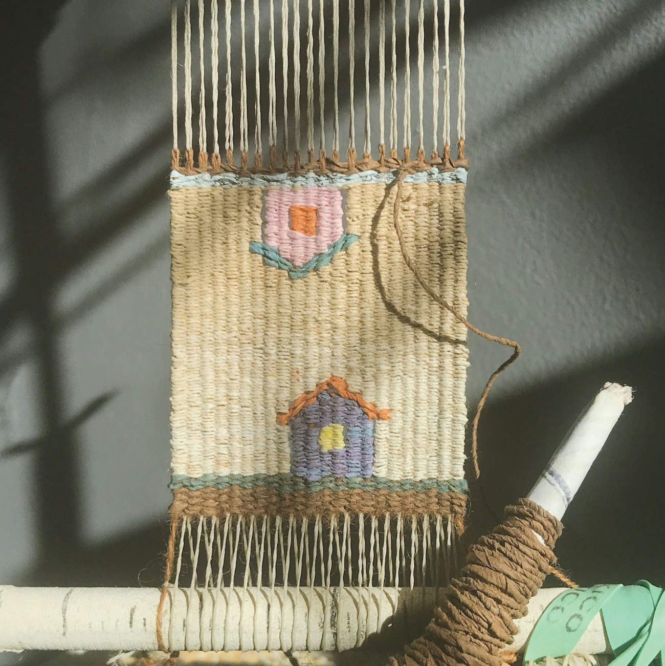 Small tapestry on the loom with two houses