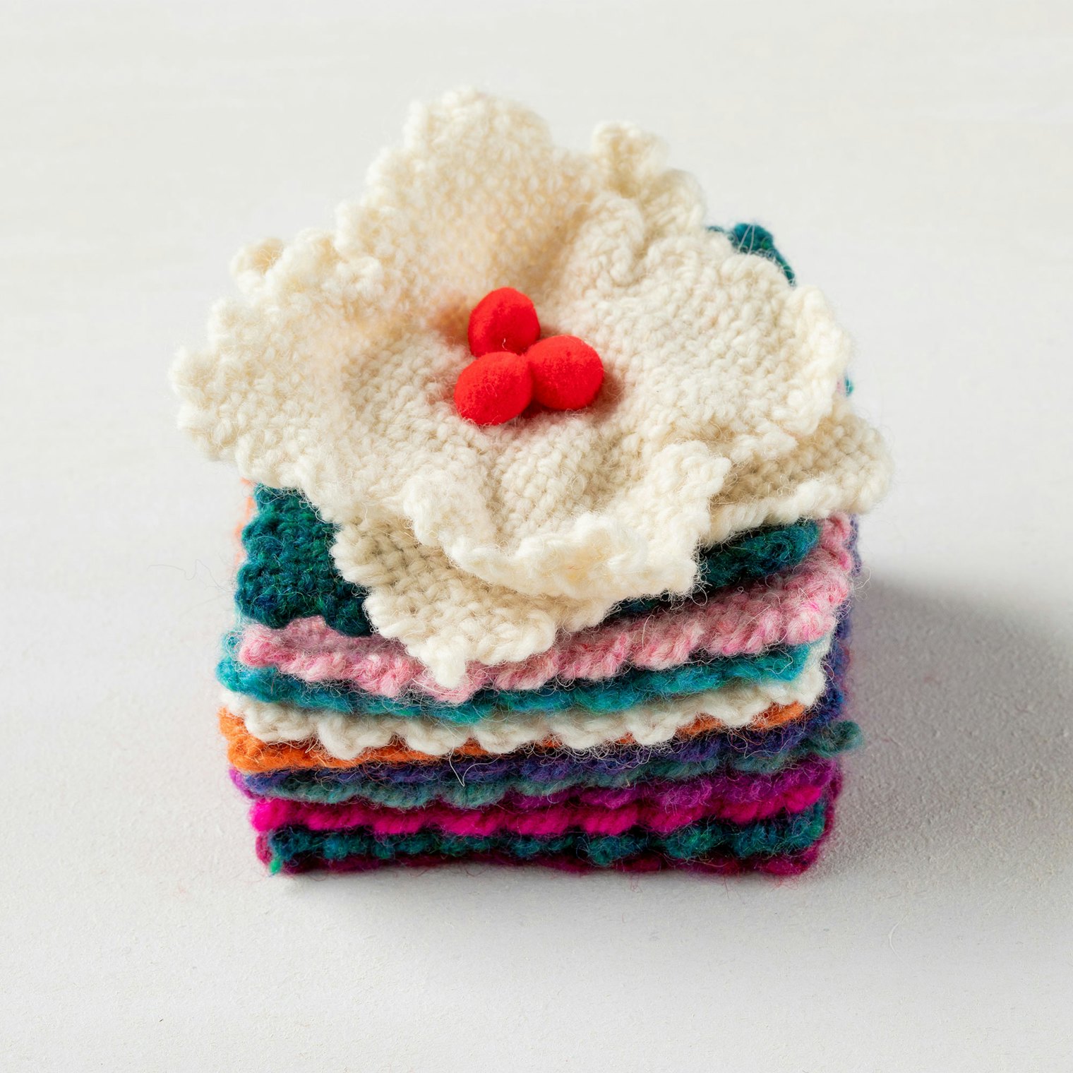A stack of pin-loom squares and a magnolia ornament