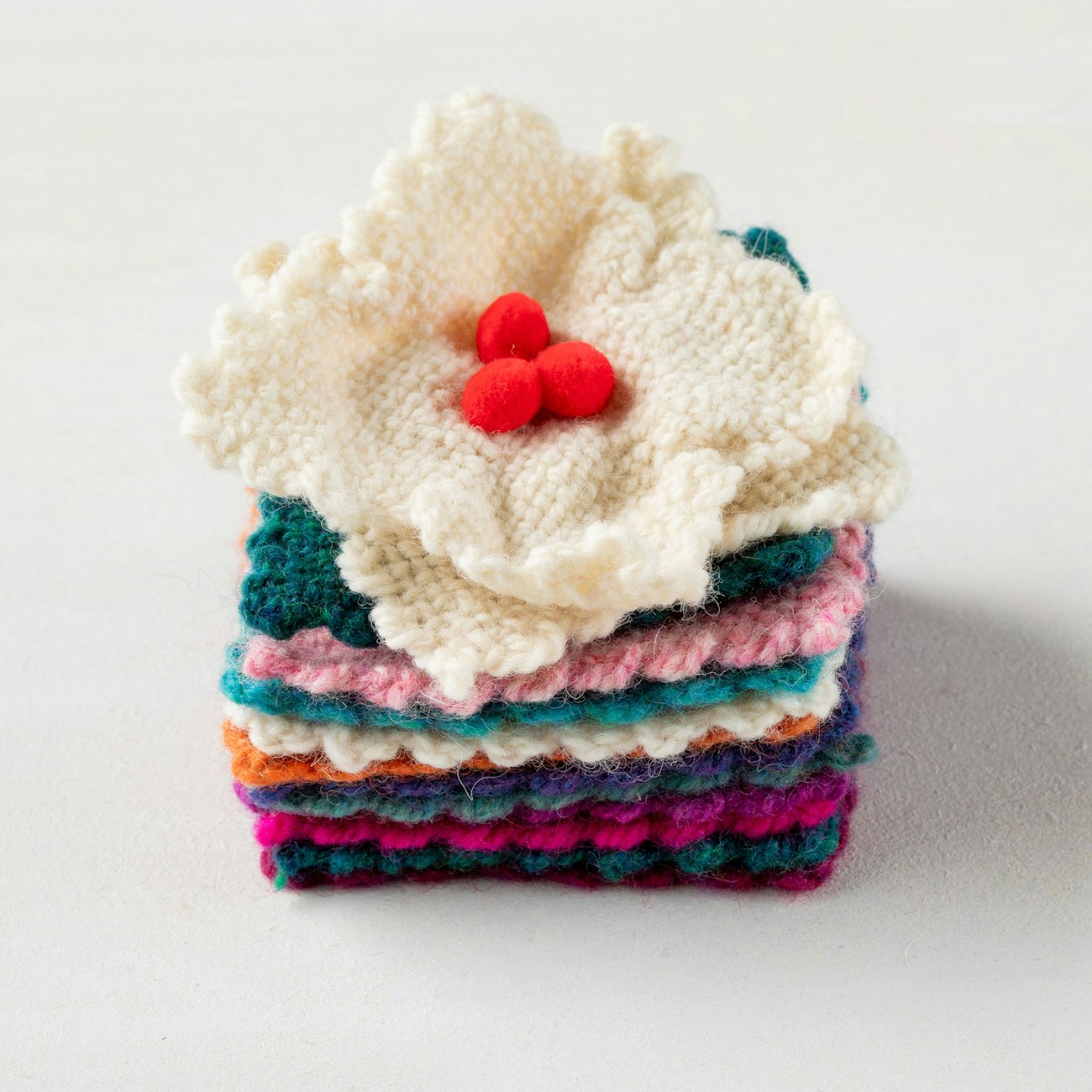 A stack of pin-loom squares and a magnolia ornament