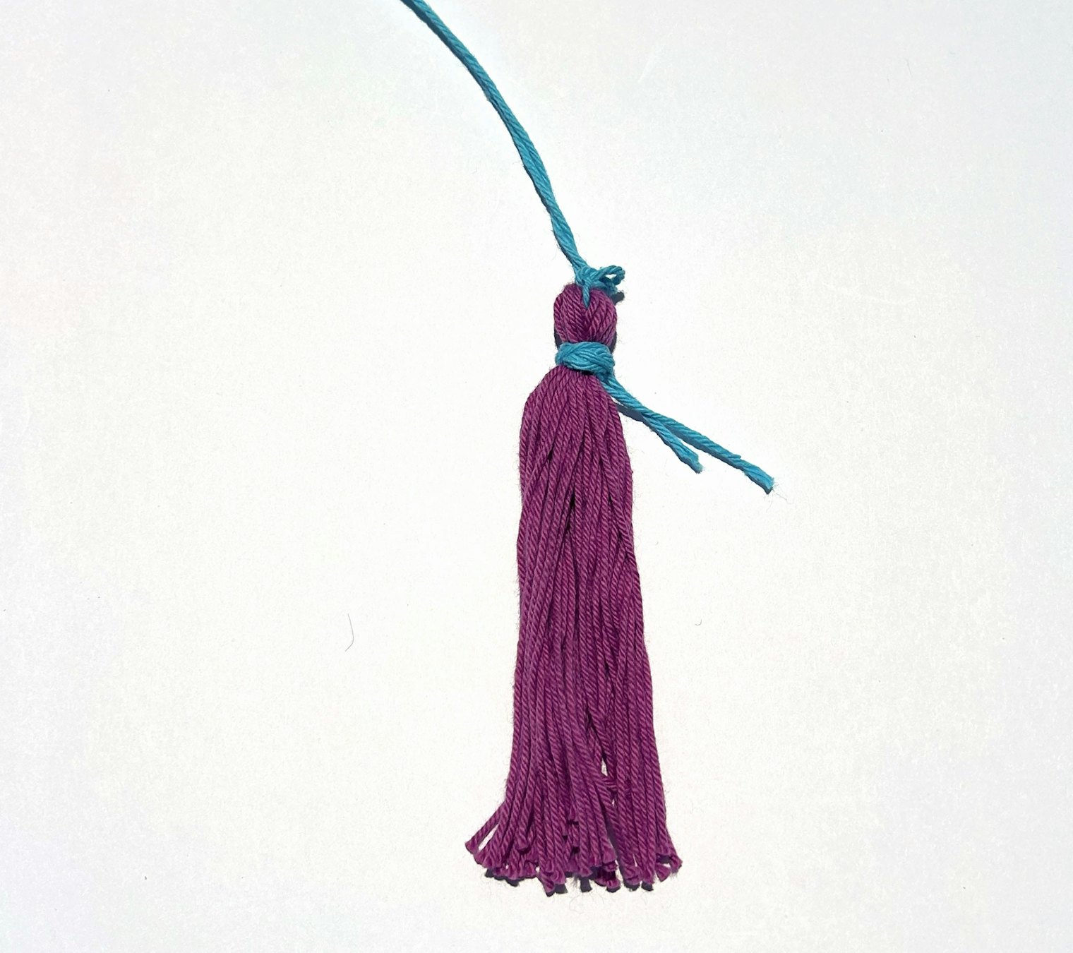A short length of yarn is wrapped around the neck of the tassel and secured with a knot.