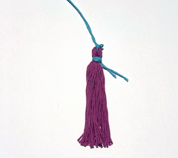 A short length of yarn is wrapped around the neck of the tassel and secured with a knot.