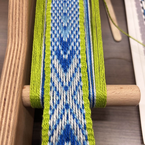 In this band, the weaver chose a vibrant lime-green border that contrasts nicely with the cooler blues used in the primary motifs.