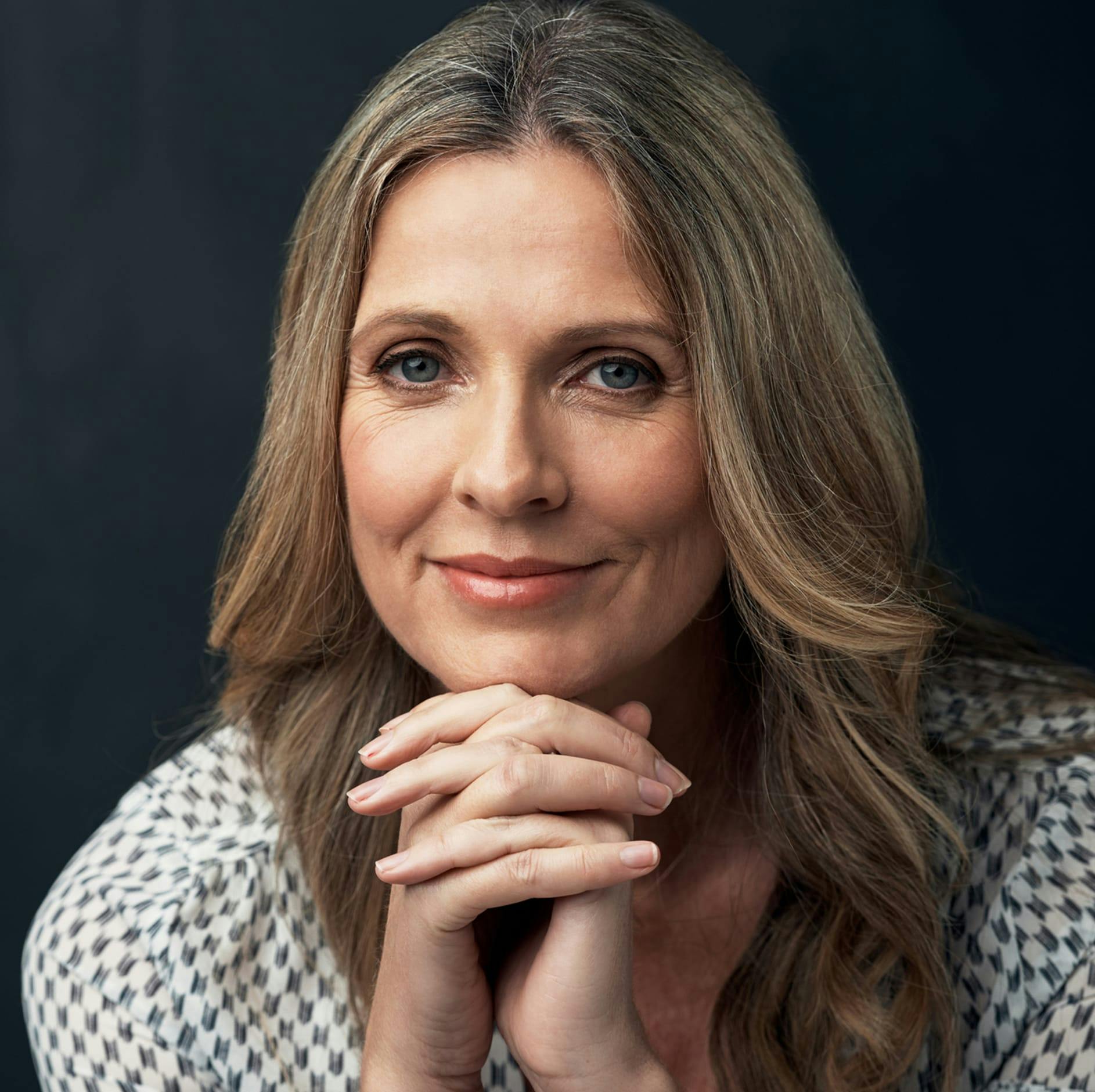 woman smiling with her hands under her chin