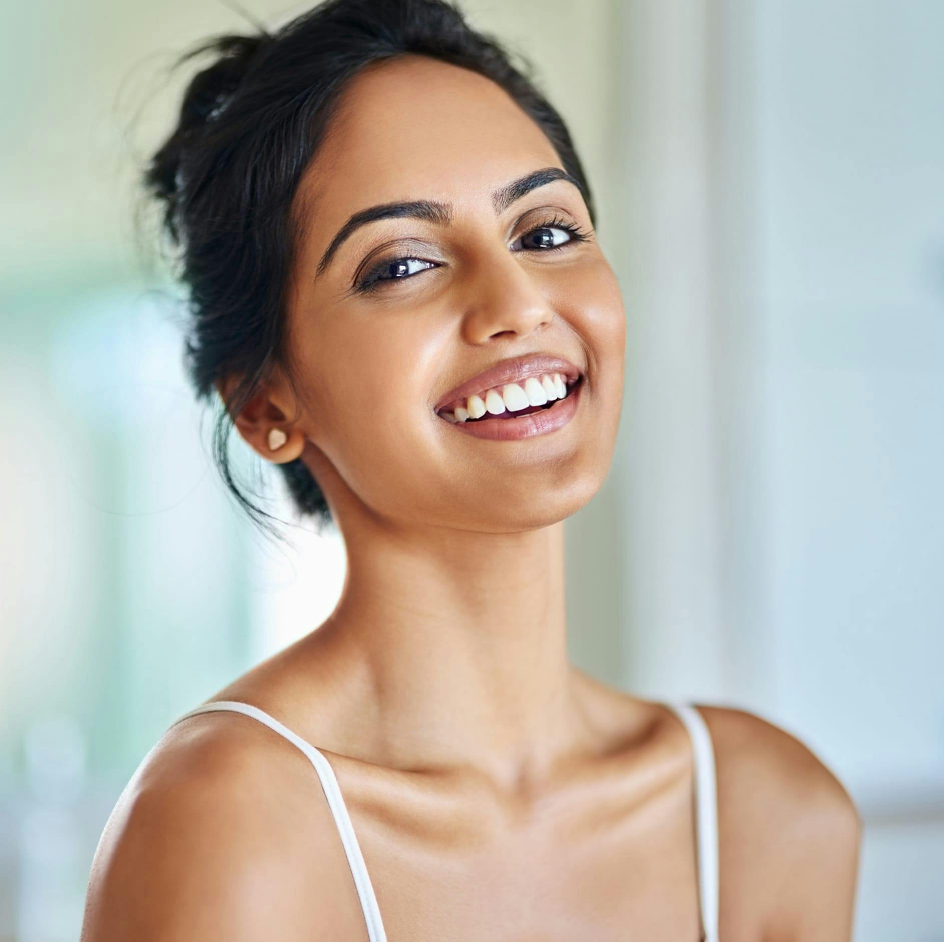 woman in a white tank top smiling