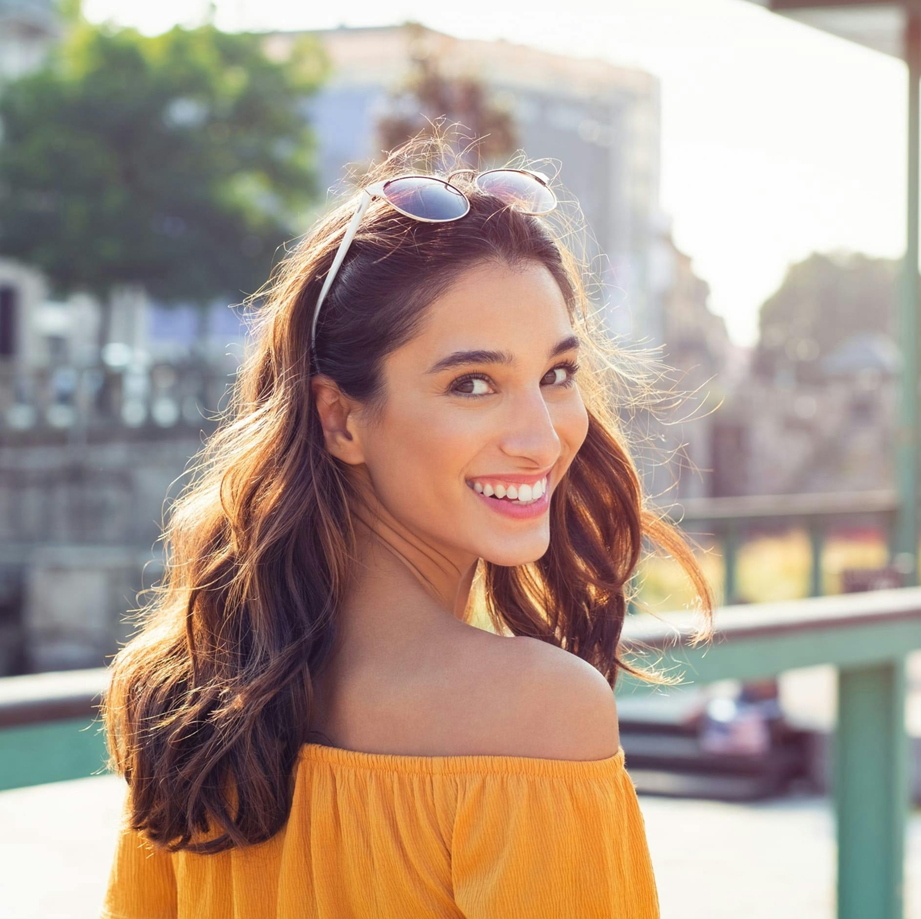 woman with a shirt off her shoulder and smiling