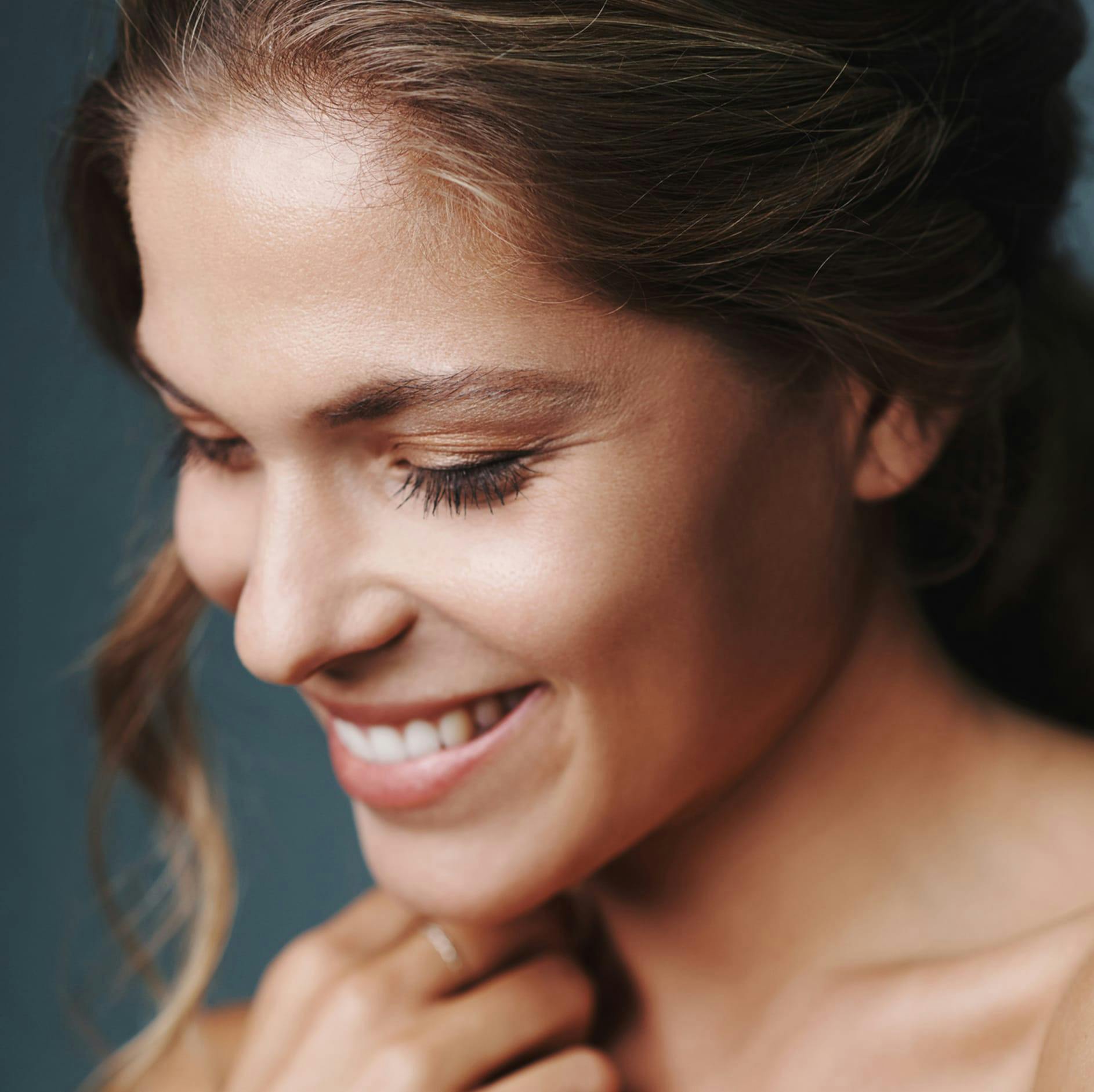 woman with her hair up smiling and looking down