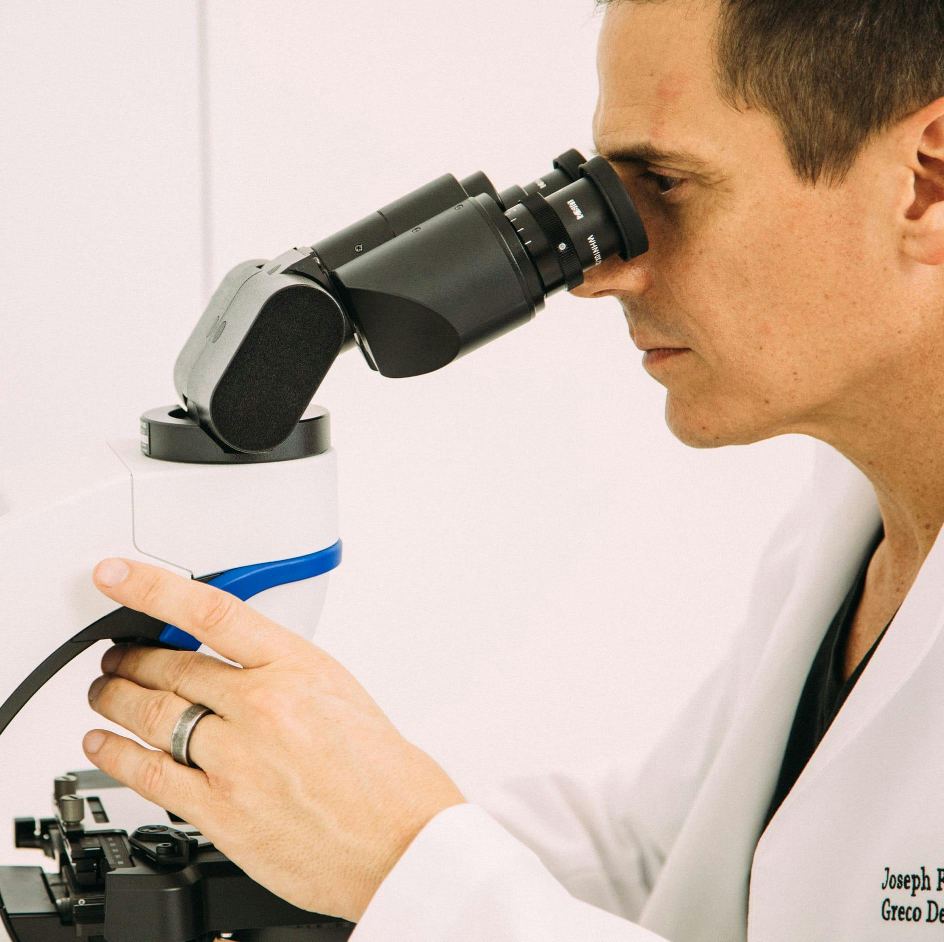 Dr. Joseph F. Greco III looking through a microscope