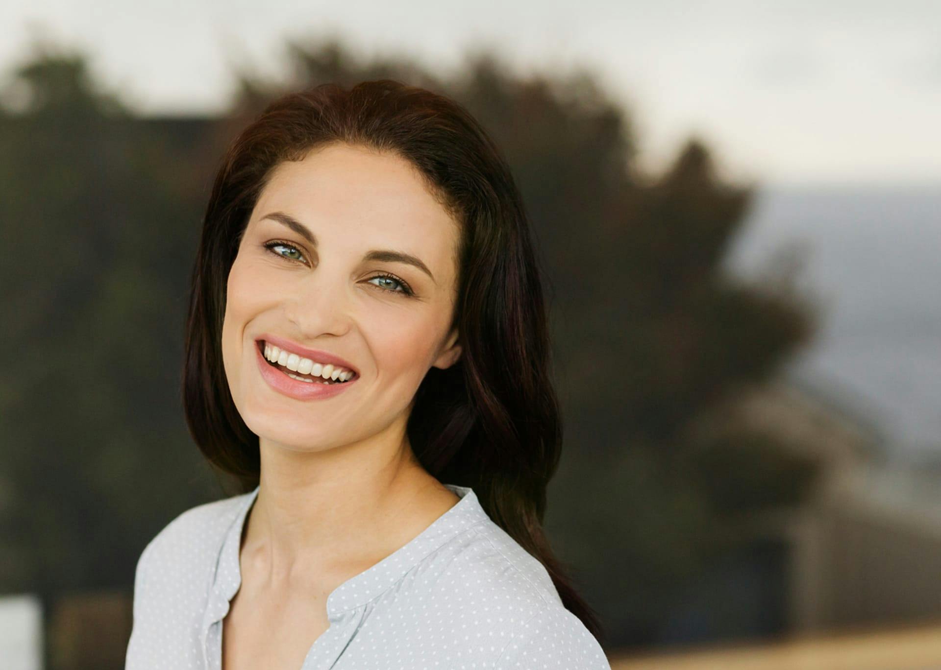 woman with dark hair smiling and a dark background