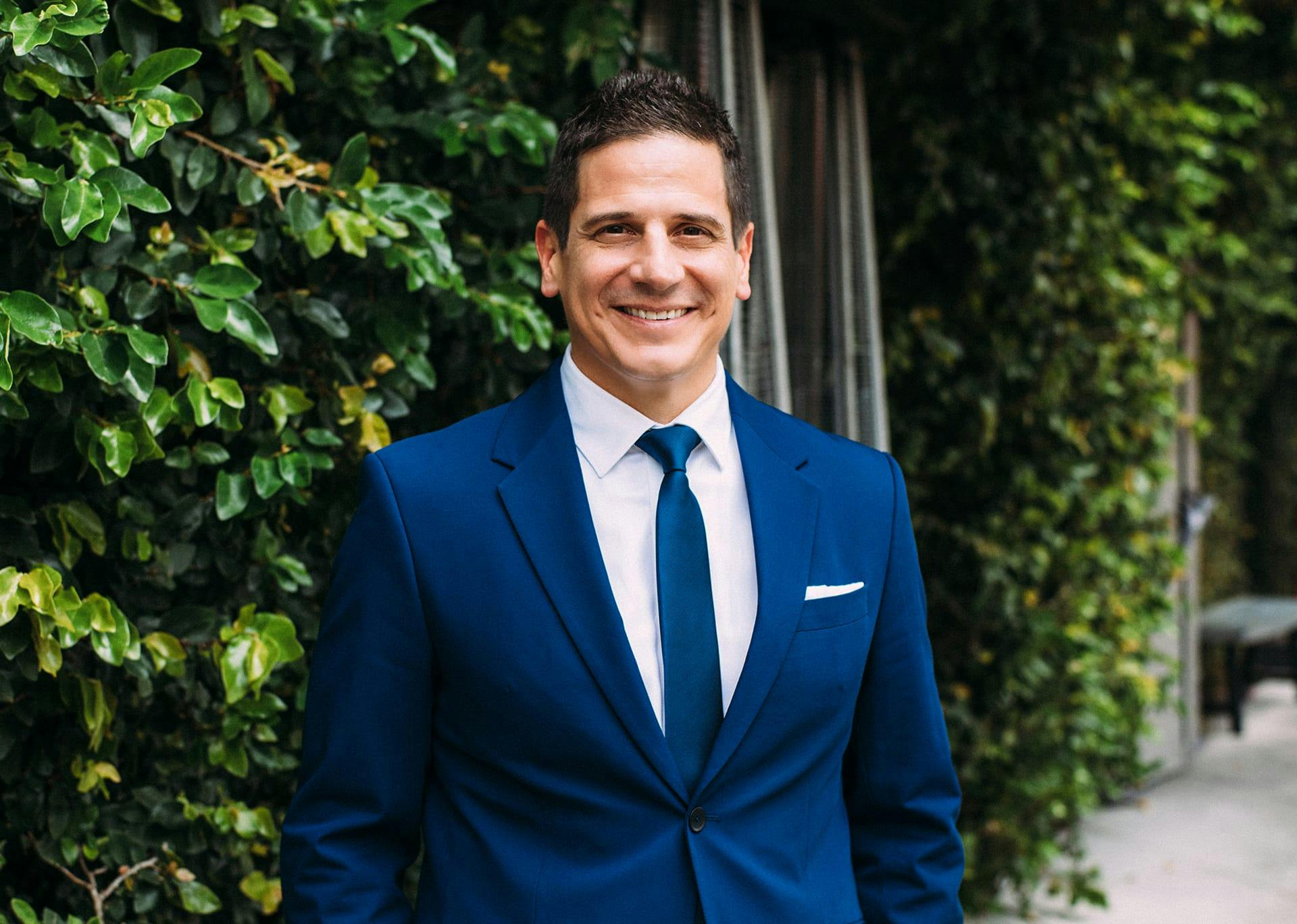Dr. Greco in a blue suit with green background