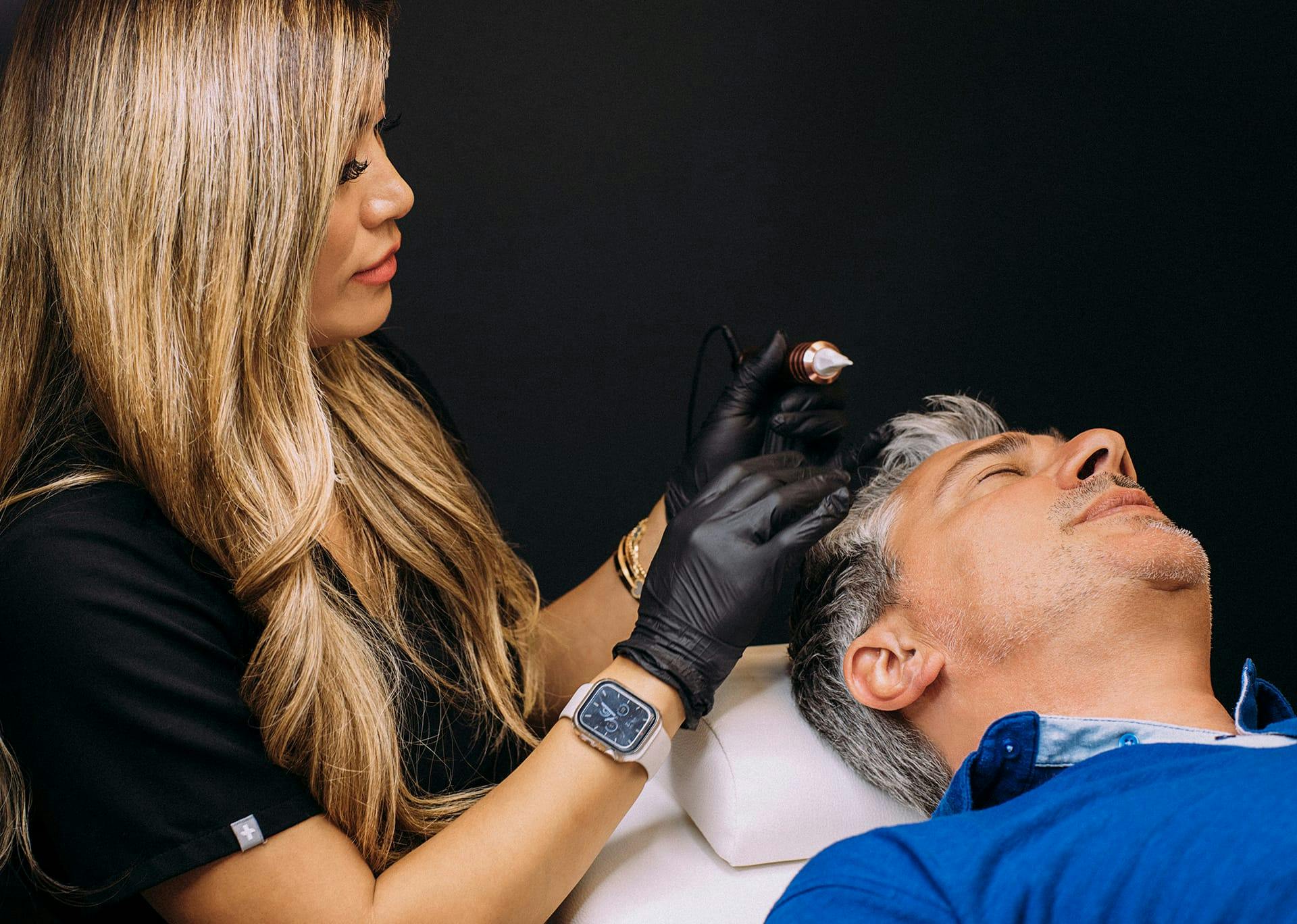 woman with performing scalp micropigmentation on a man