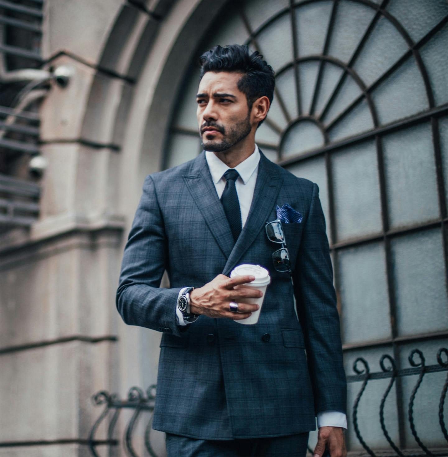 Man in a suit with a coffee cup looking to camera right