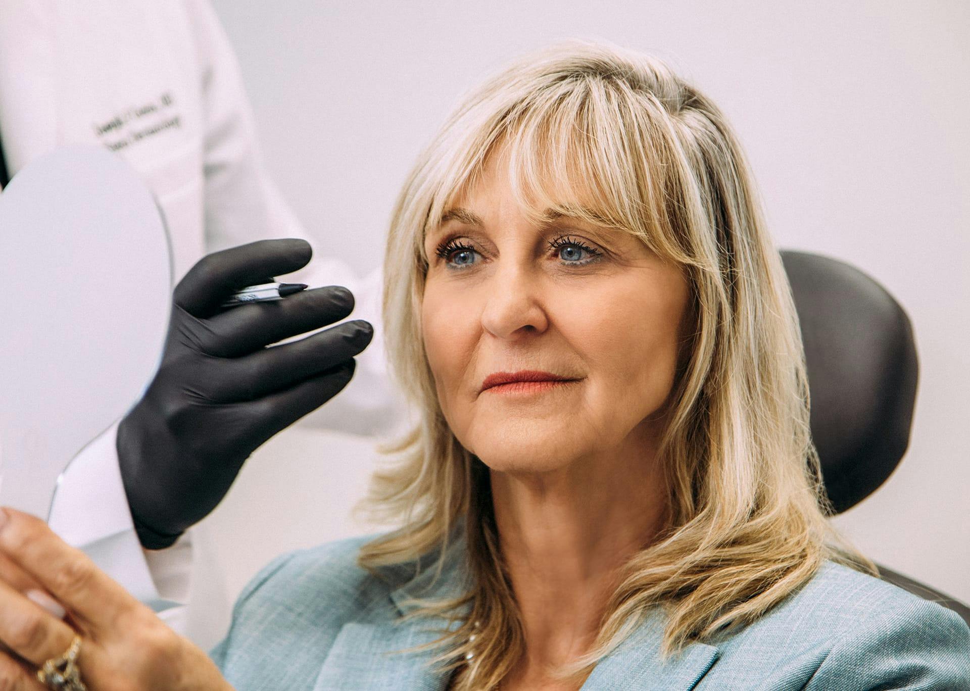 woman with blonde hair looking in a mirror