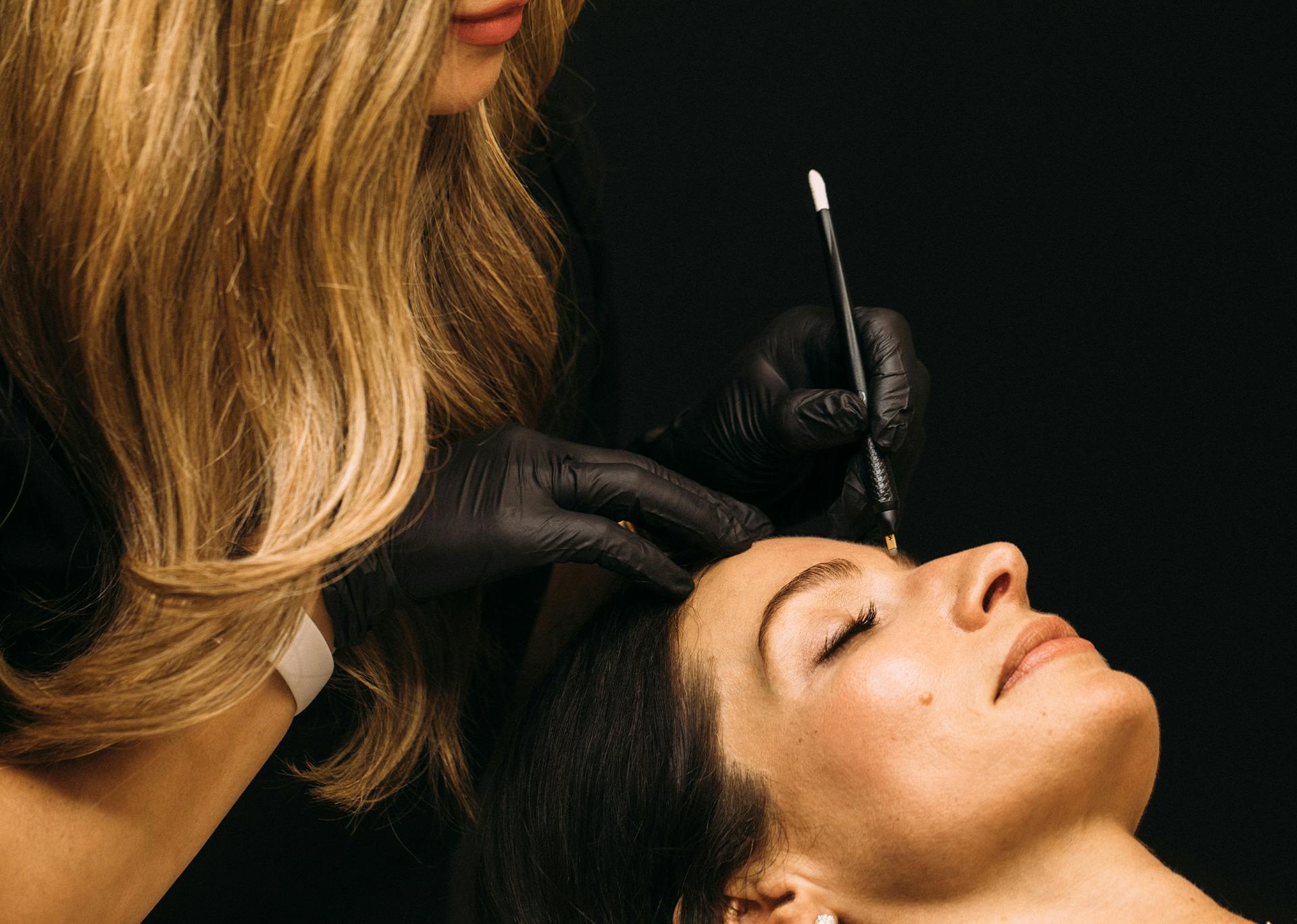 woman doing eyebrow microblading on another woman