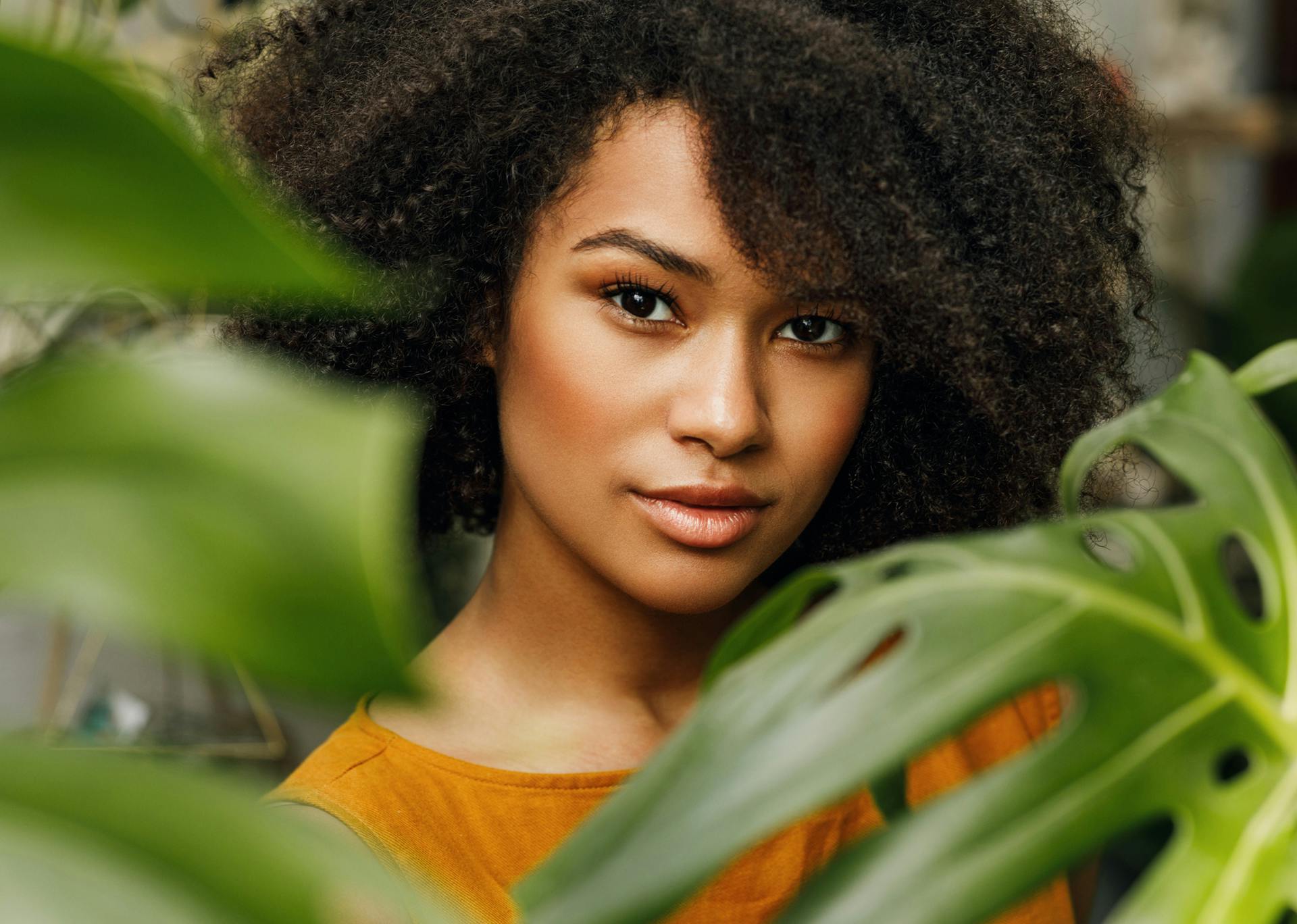 woman with brown hair and brown eyes between two plants