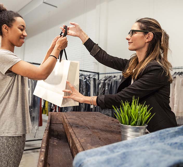 Retail Manager handing a shopping bag to customer