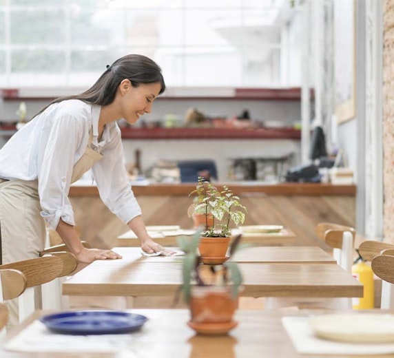 Hospitality worker wiping a table. 