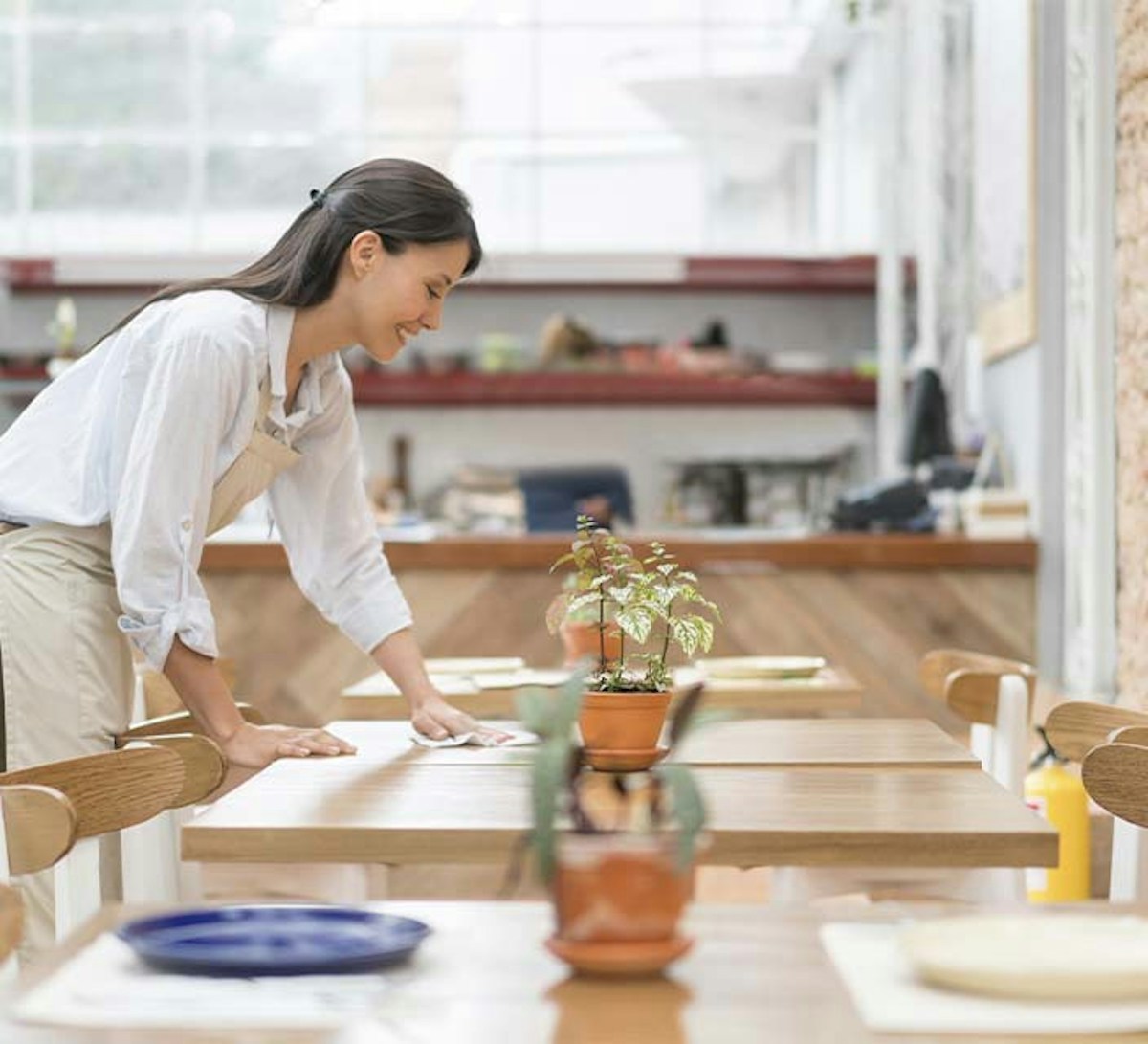 Hospitality worker wiping a table. 