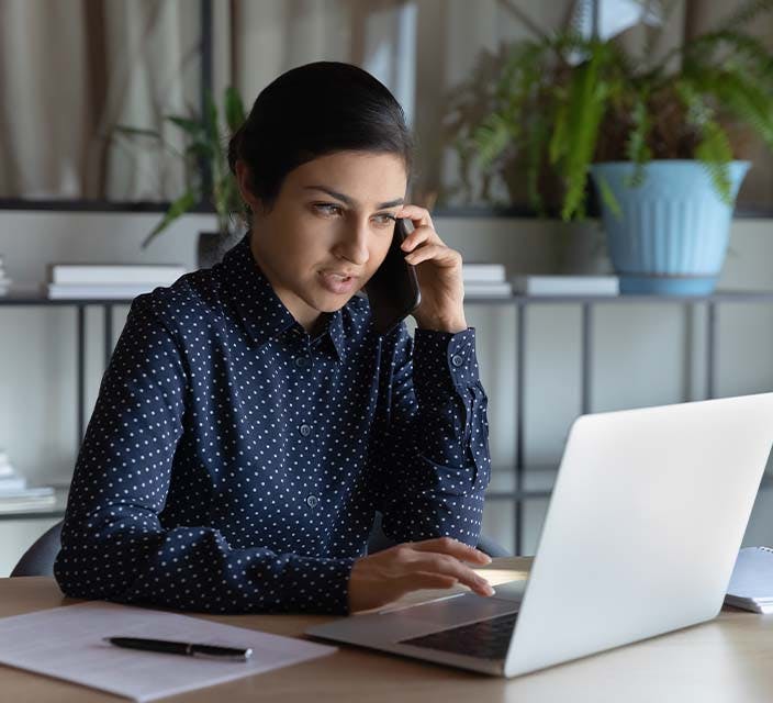 Female working on laptop while talking on the phone