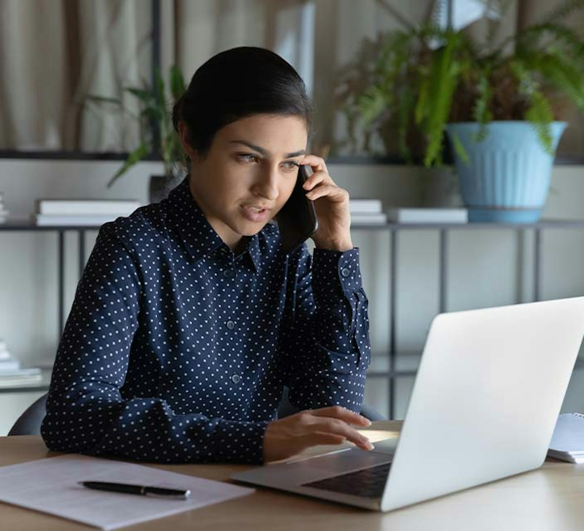 Female working on laptop while talking on the phone 