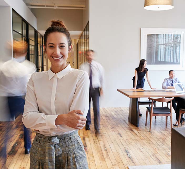 Female standing in office with co workers