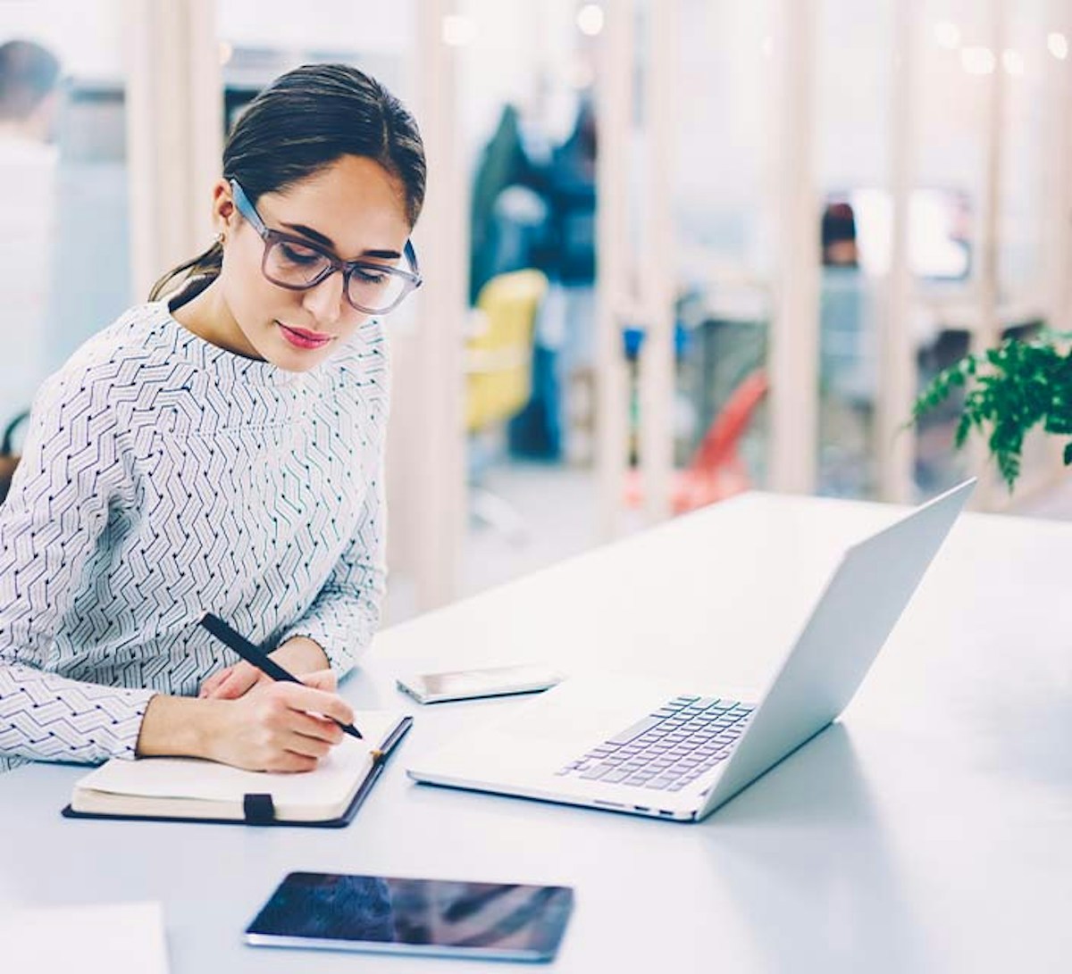 Female taking notes while working on laptop