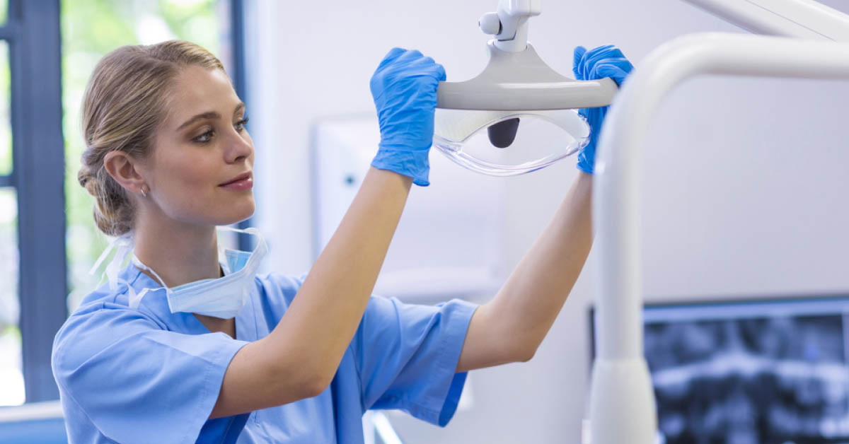 Dental assistant adjusting light above patient chair