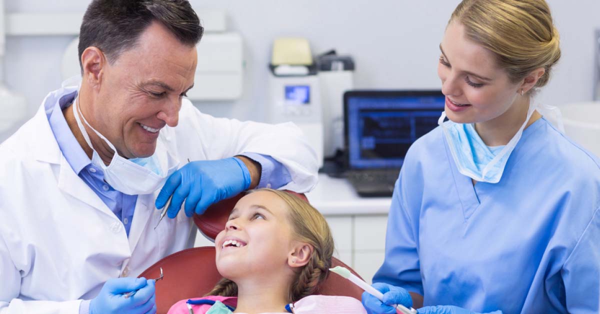 Dentist and dental assist talking to child patient