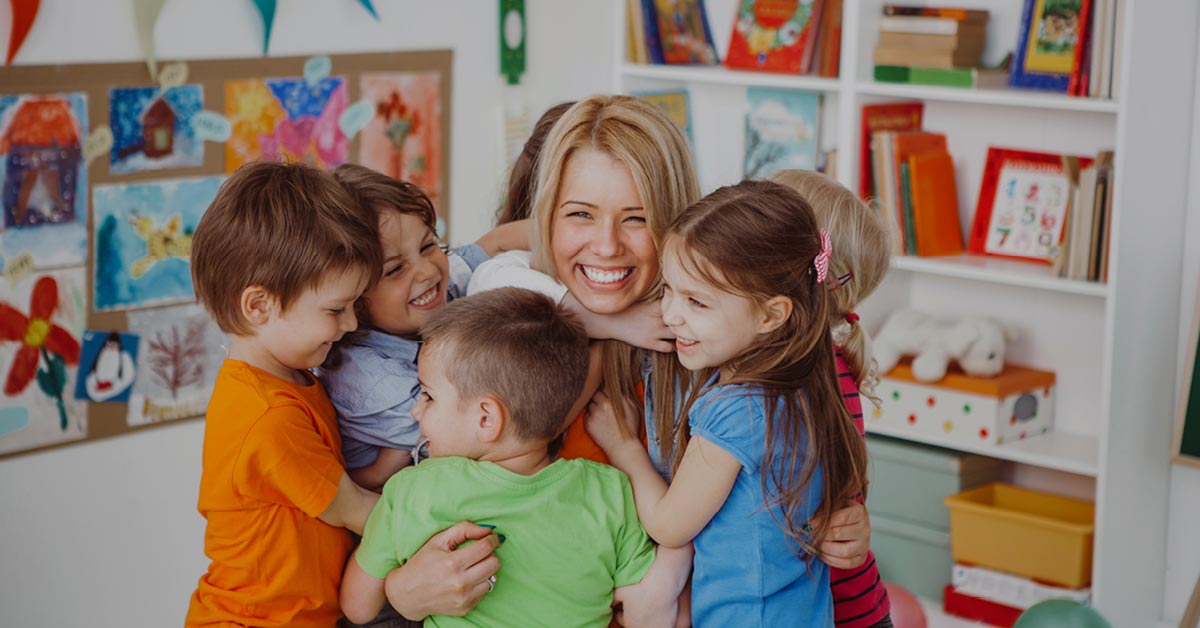 Childcare worker hugging a group of young students