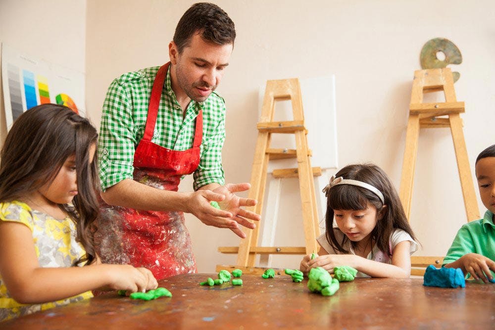 Male childcare worker assisting young students